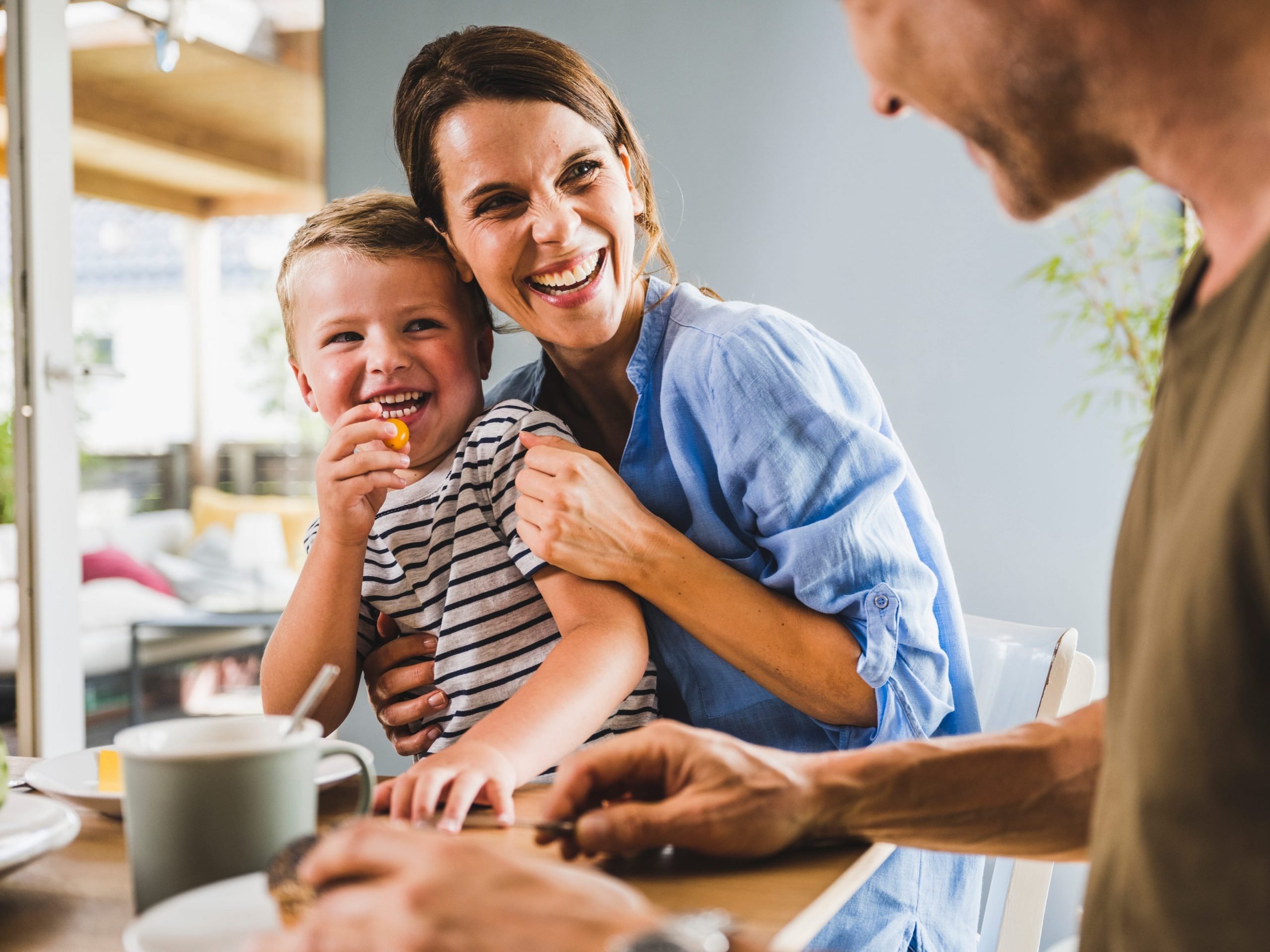 Smiling mother and son looking at father having breakfast at home