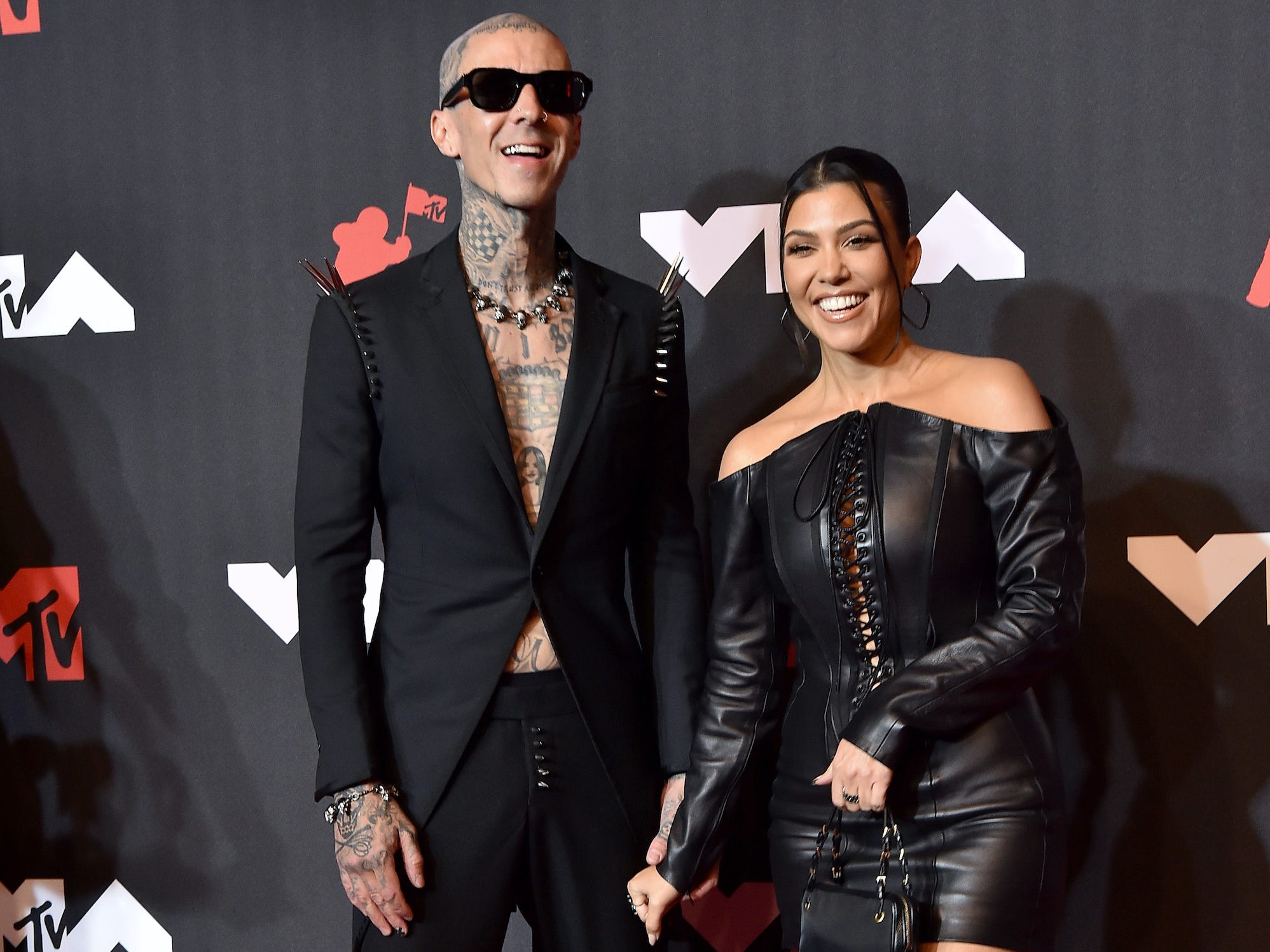 Travis Barker and Kourtney Kardashian smile on the VMAs red carpet.
