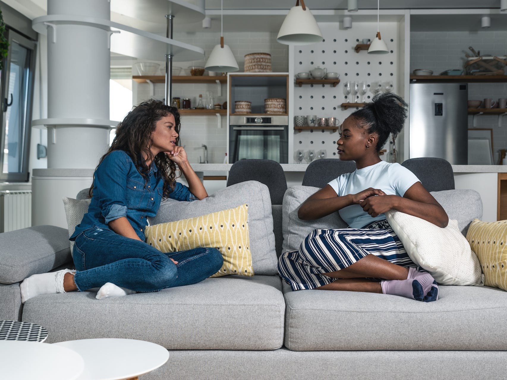 Two roommates chatting while sitting on the sofa.