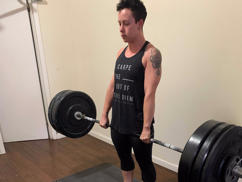 fitness reporter deadlifting barbell weight in home gym