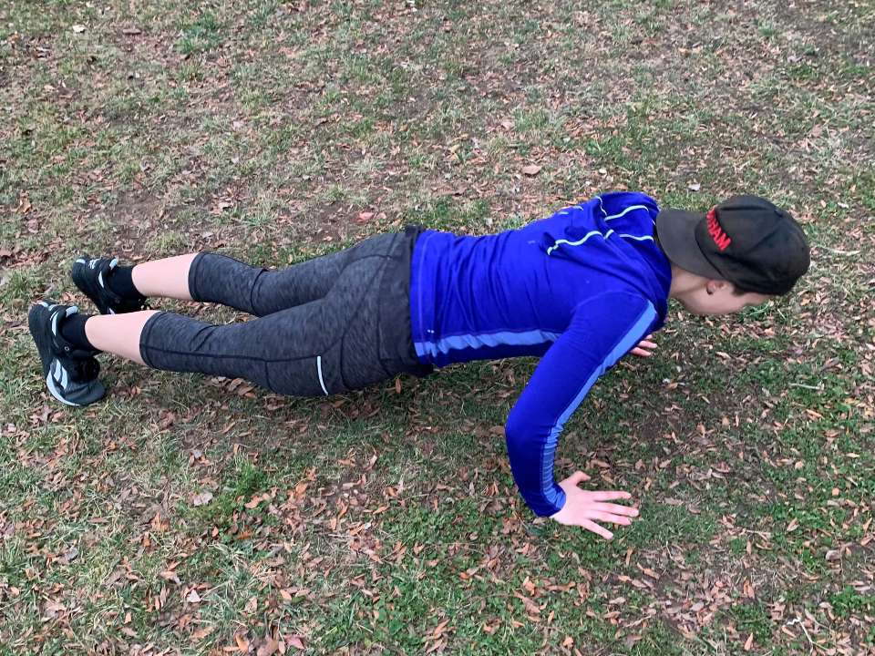 fitness reporter doing push-ups in the grass
