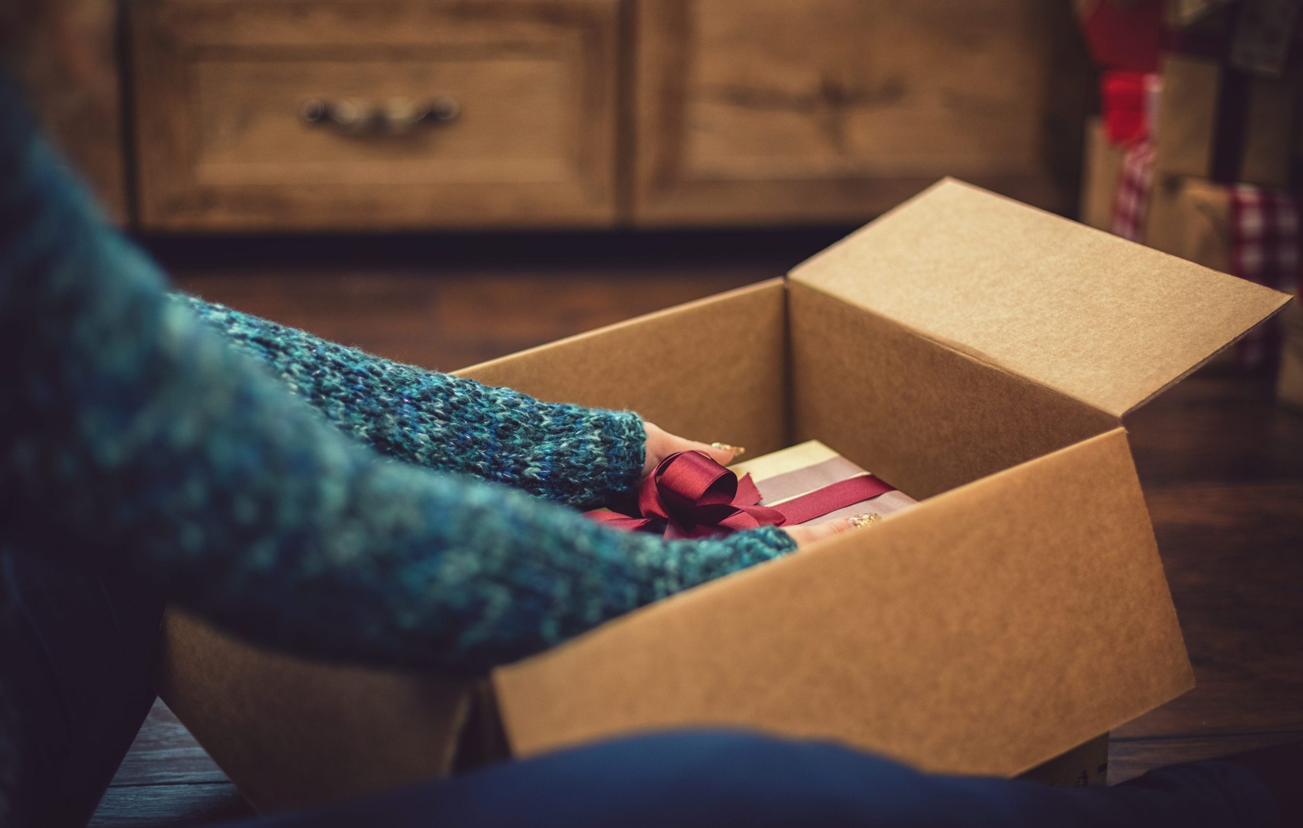 A person opening a shipping box with gifts in it.