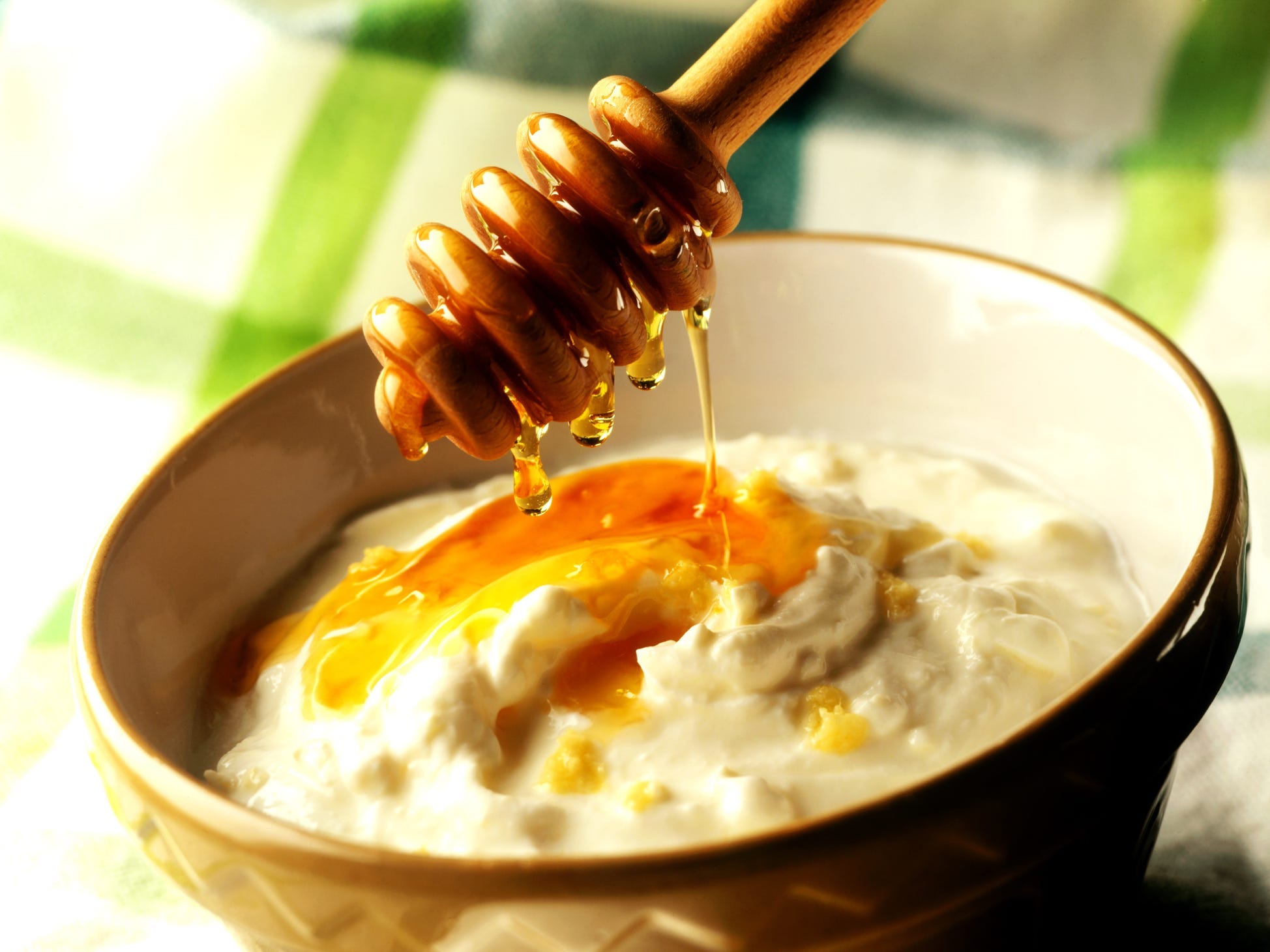 Honey getting drizzled over Greek yoghurt.