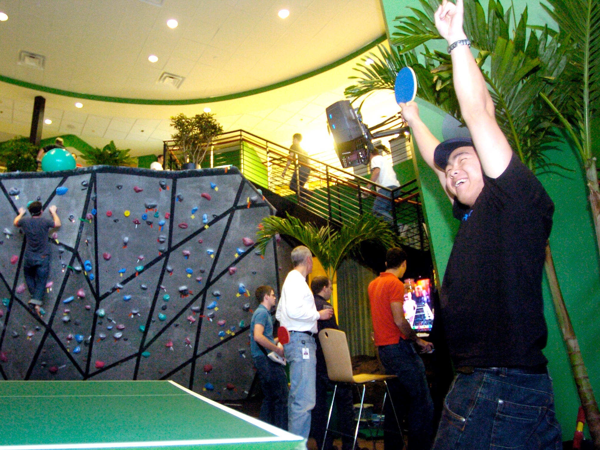 Jin Pak, right, a 3D data specialist, celebrates a table tennis win at Google's Boulder offices on Tuesday afternoon. After working all day at their computers, Google employees can unwind with a climbing wall, video games, table tennis, and massage.