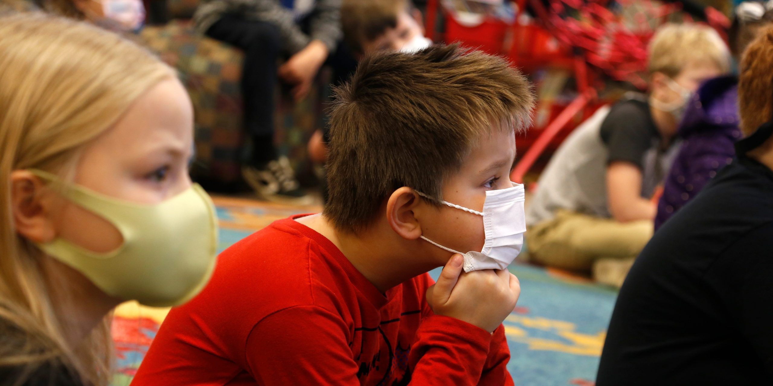 A child listens at school while wearing a mask.