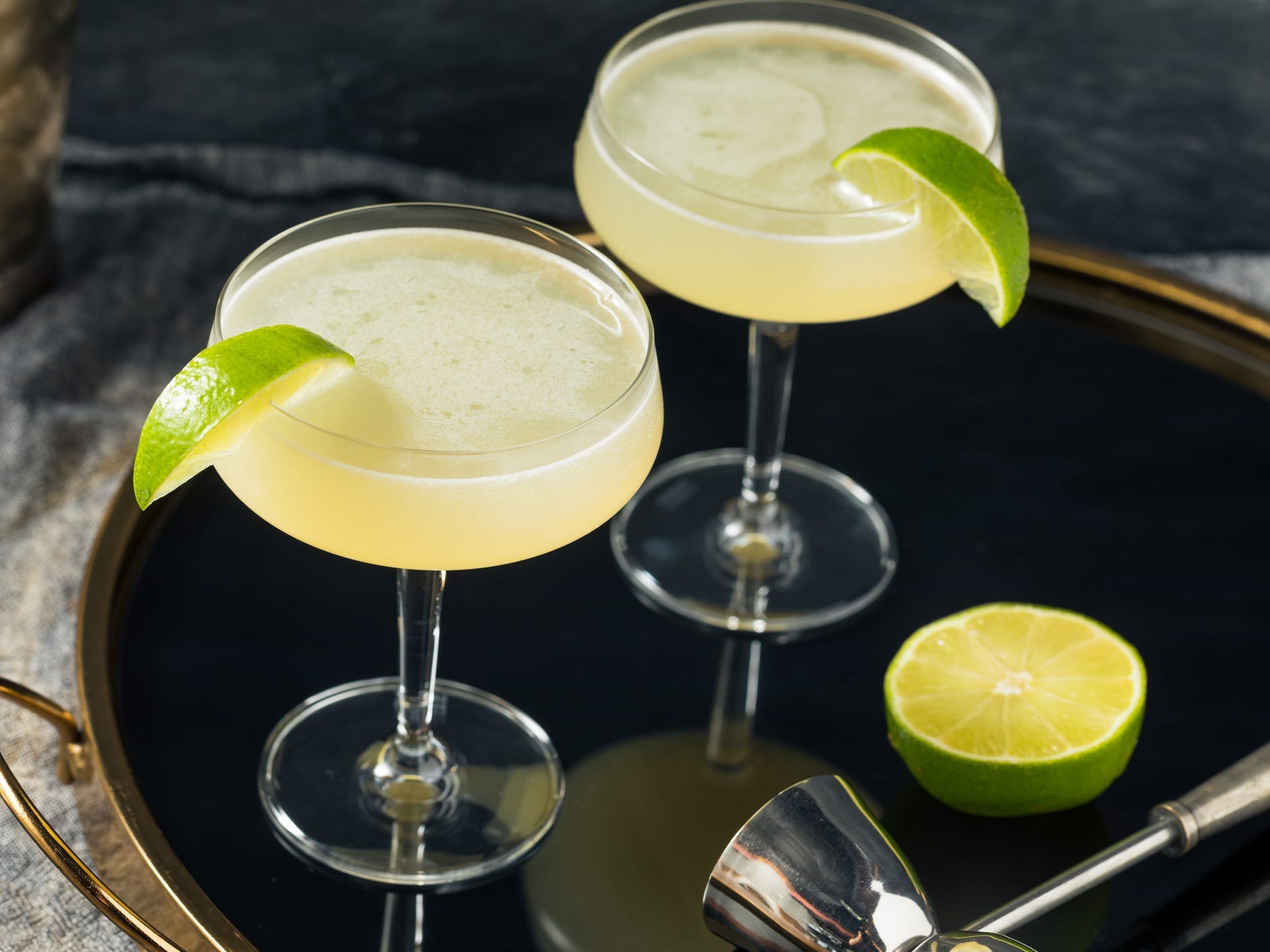 Two glasses of gimlet cocktail with lime garnishes.