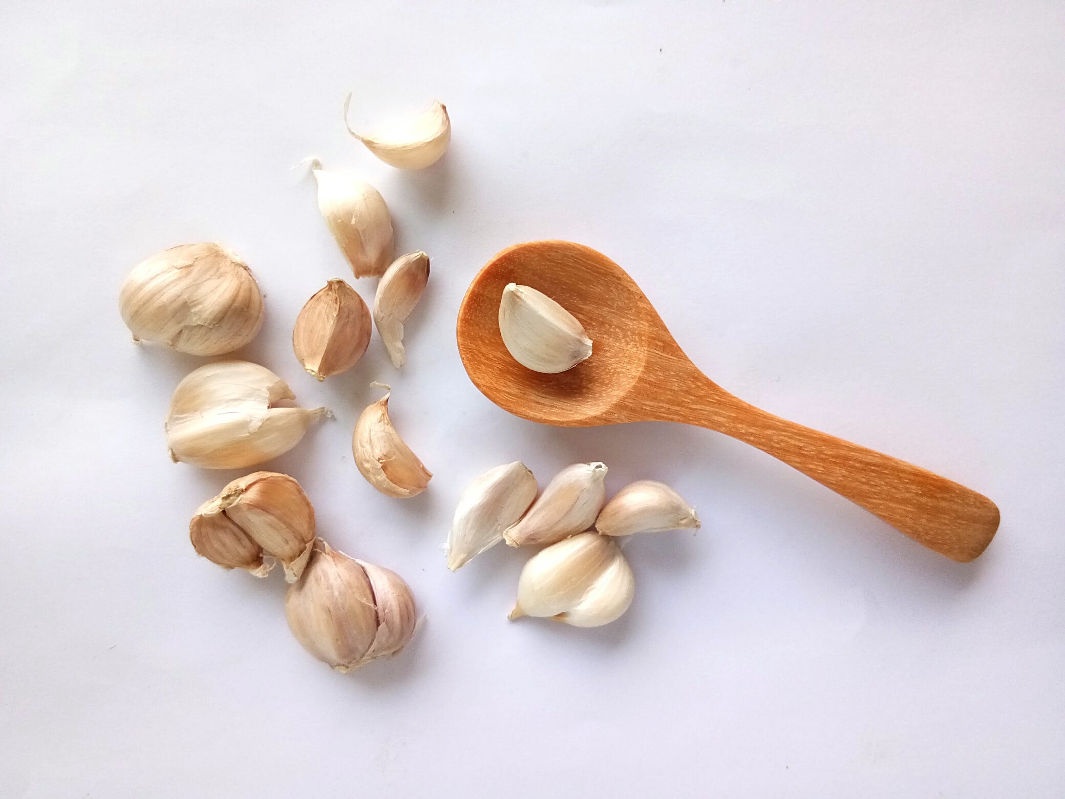 Close-up of garlic cloves with a wooden spoon.