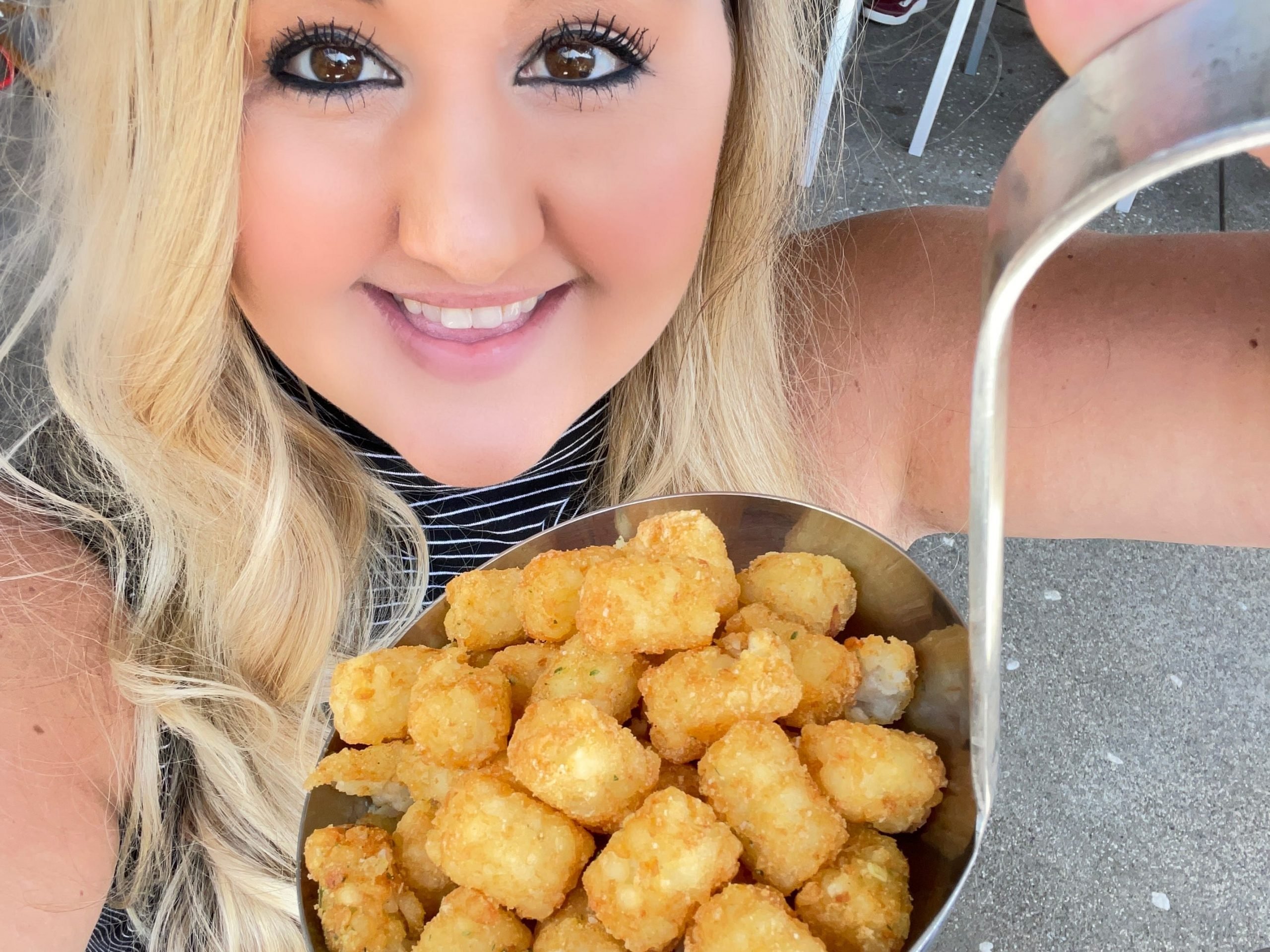 carly holding a ladel full of tater tots at disneyland