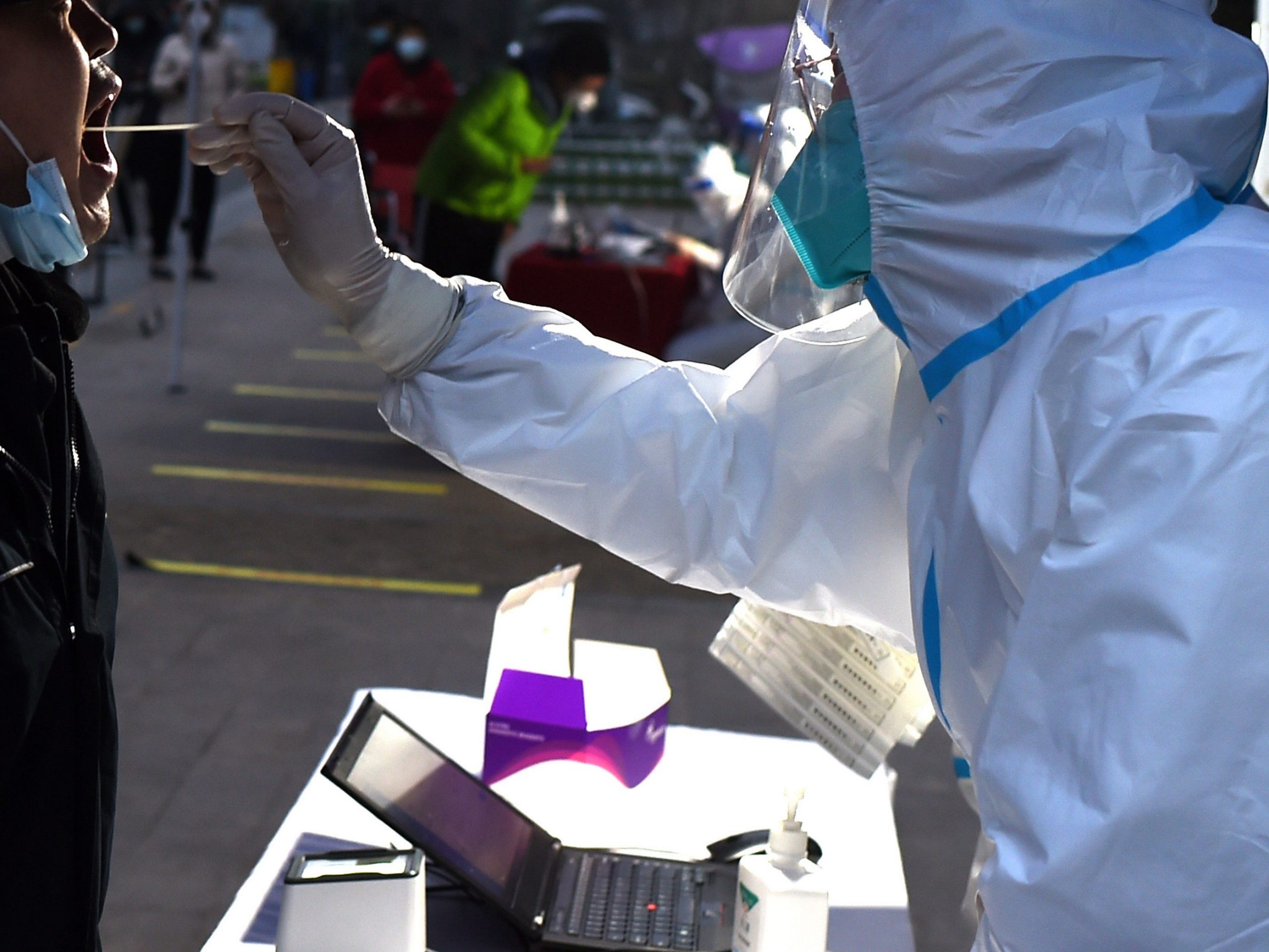 A staff member conducts nucleic acid tests for residents at a residential community in Xi 'an, Shaanxi province, Dec 23, 2021. Since midnight on December 23, xi 'an city started closed management, all staff to carry out a new round of nucleic acid testing.