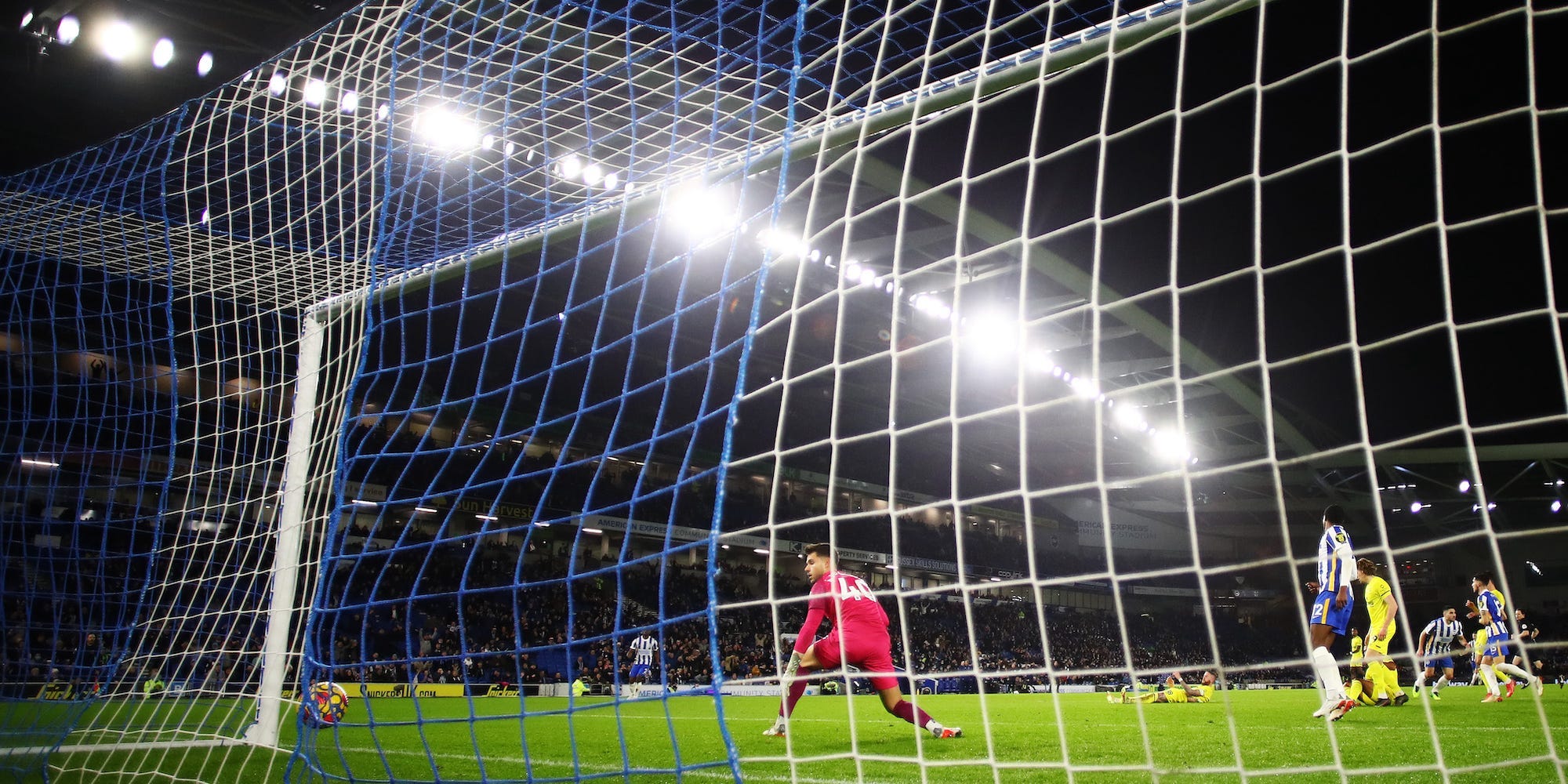 Alvaro Fernandez of Brentford looks at the ball in the back of the net as Neal Maupay of Brighton & Hove Albion celebrates after scoring their team's second goal during the Premier League match between Brighton & Hove Albion and Brentford at American Express Community Stadium on December 26, 2021 in Brighton, England.