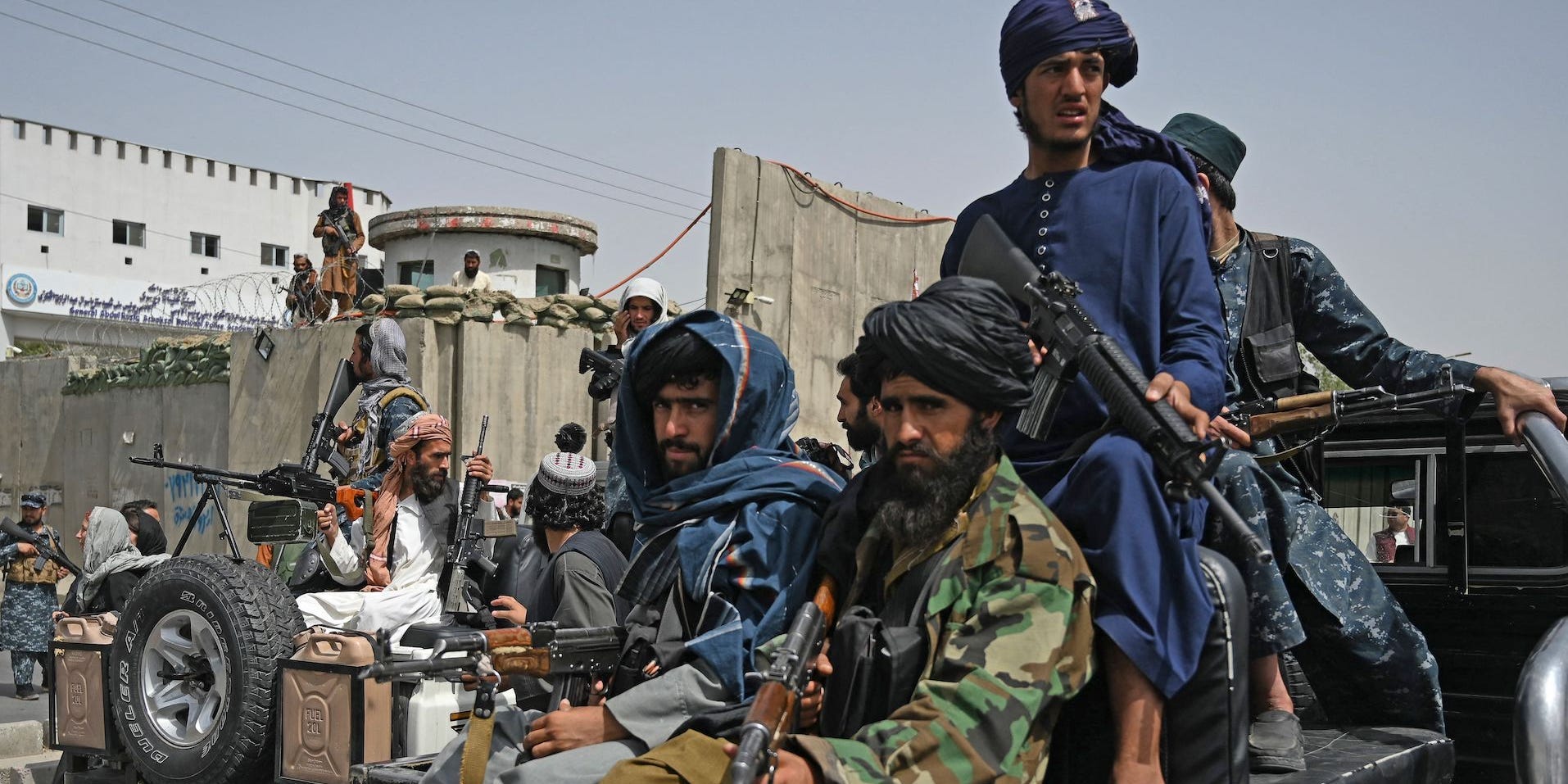 Taliban fighters holding guns on the back of a truck