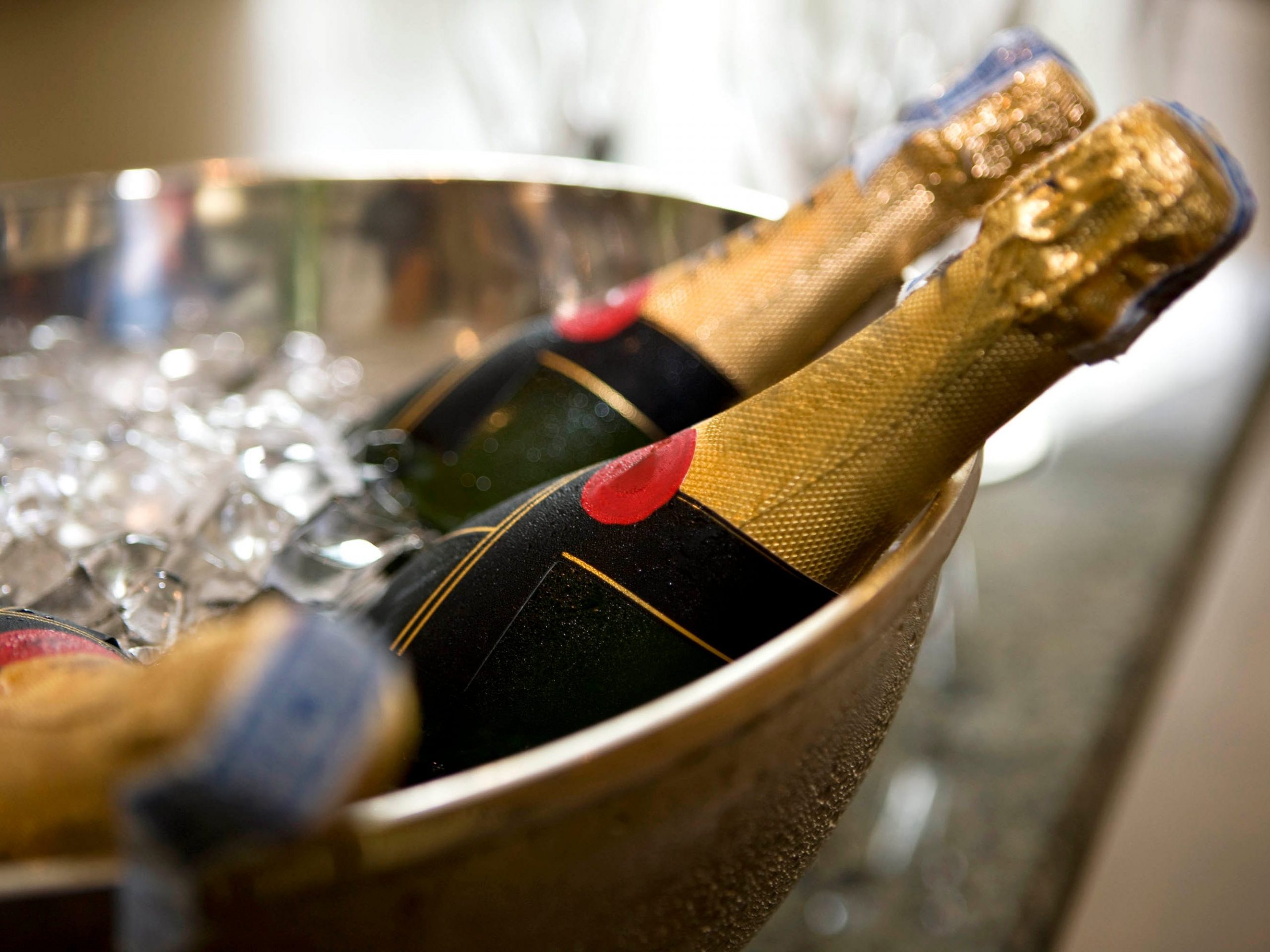Three bottles of unopened Champagne sitting in a large bowl of ice