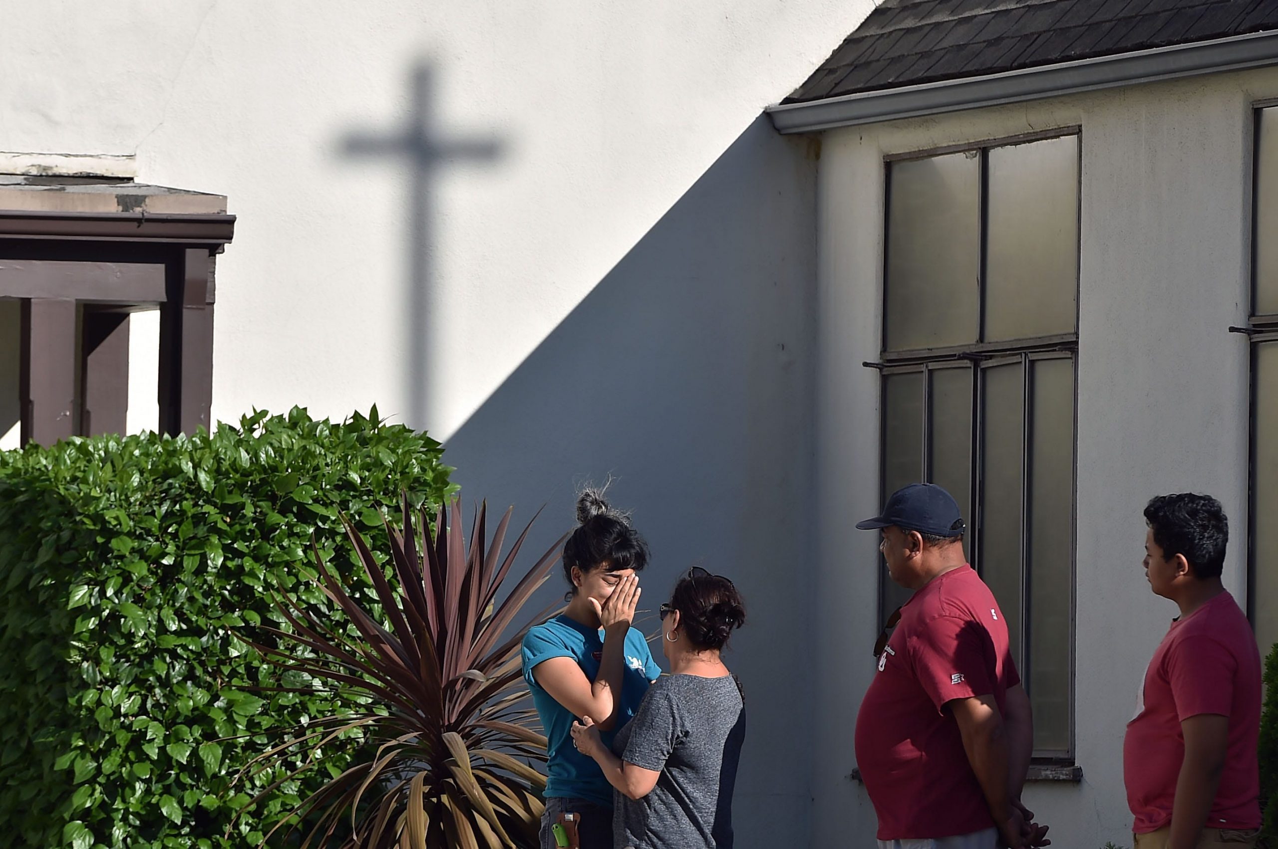 Trader Joe's employees comfort each other after a tense hostage situation against the backdrop of a cross.