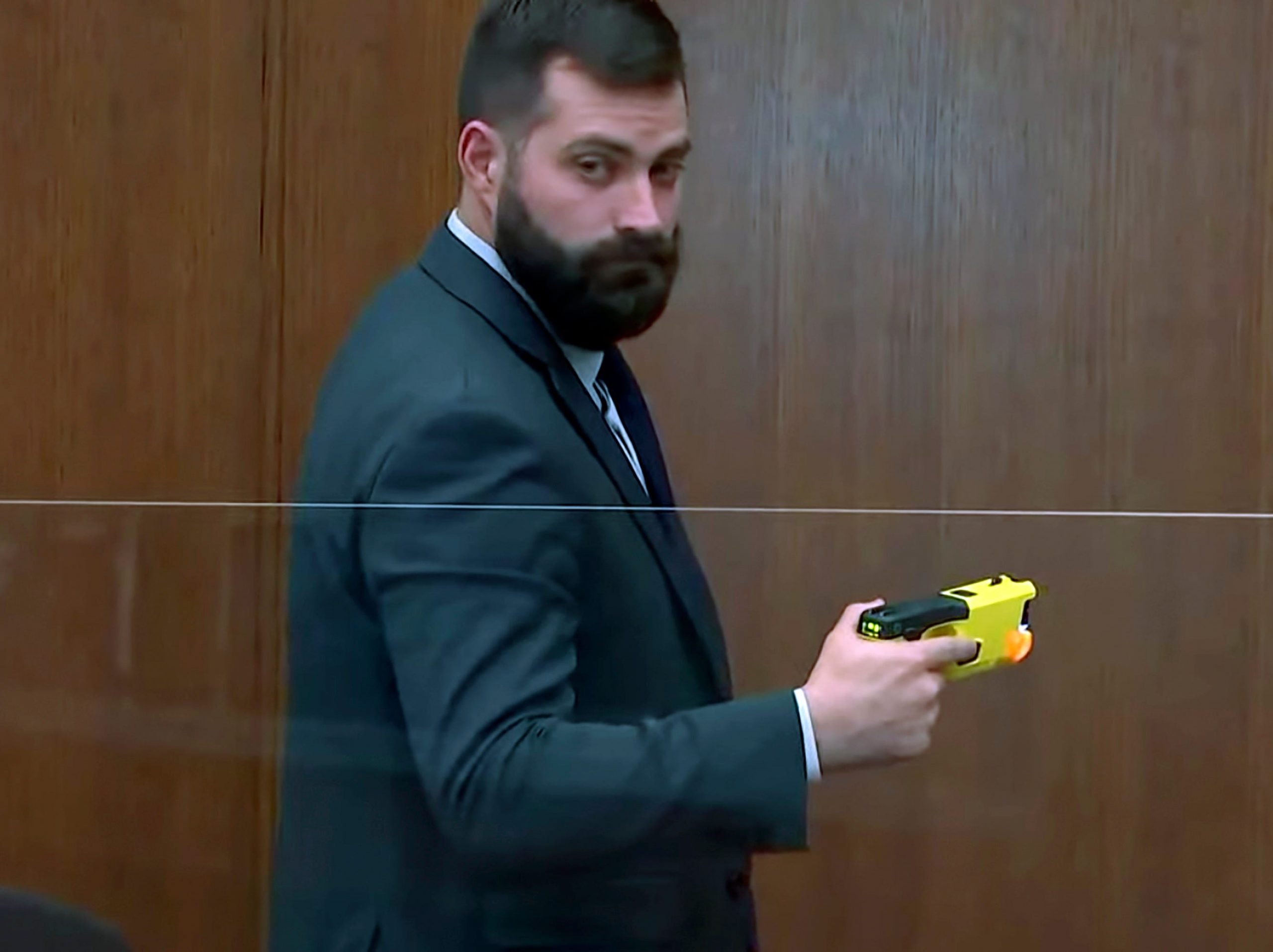 Sam McGinnis, senior special agent with the Minnesota Bureau of Criminal Apprehension, holds the taser of Brooklyn Center police Officer Kim Potter as he testifies while Hennepin County Judge Regina Chu presides over court Monday, Dec. 13, 2021, in the trial of Potter in the April 11, 2021, death of Daunte Wright, at the Hennepin County Courthouse in Minneapolis.