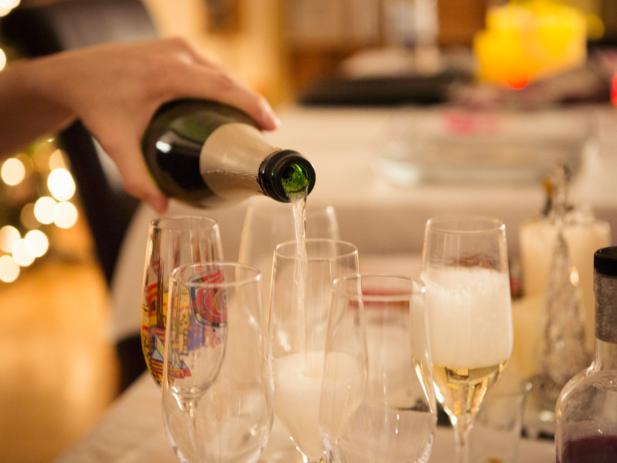 Person pours Champagne into flutes at house party