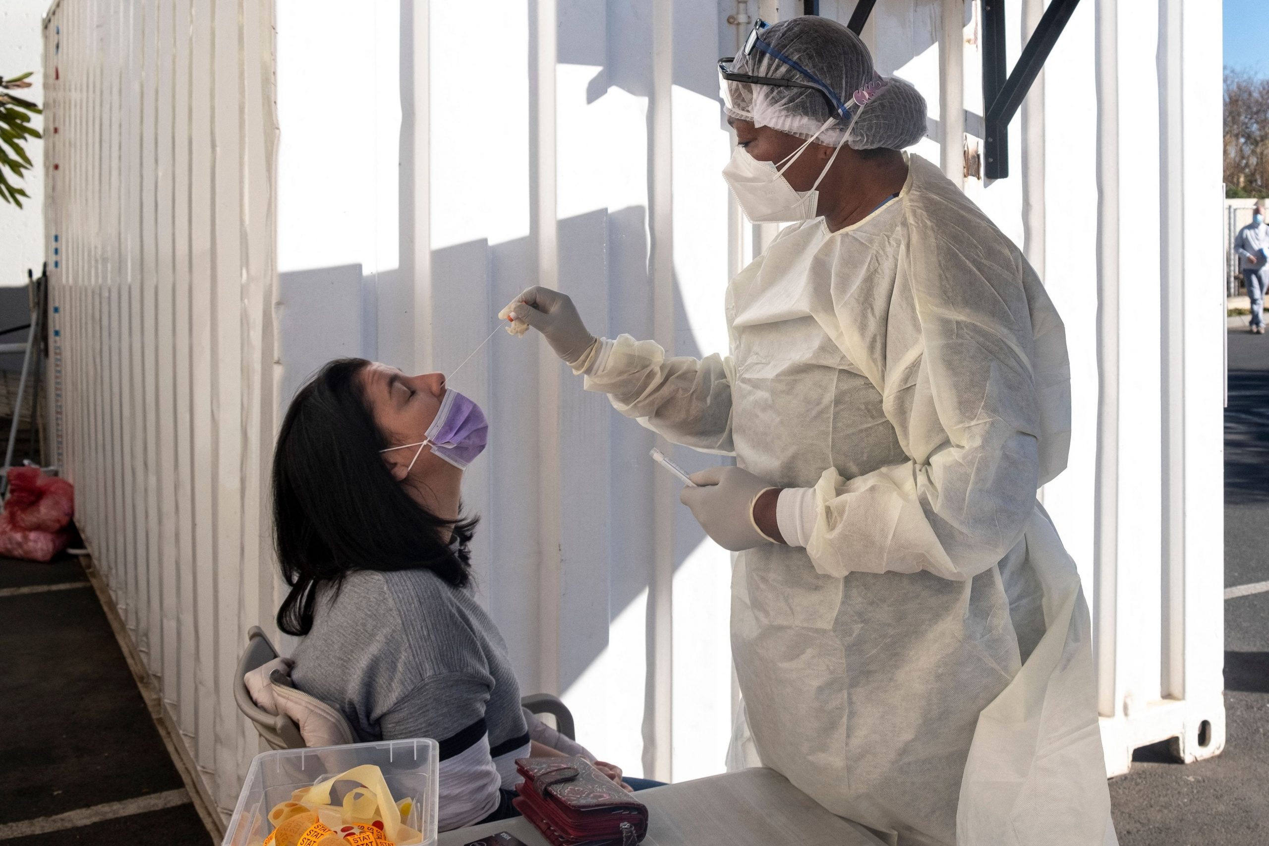 A woman receives a swab test from a medical professional wearing Personal Protective Equipment.