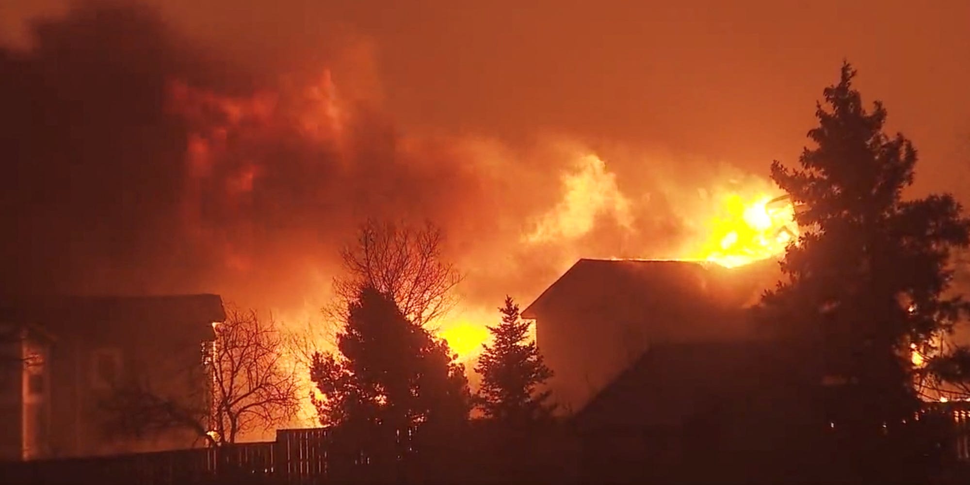 A building and trees lit up by fire in Colorado