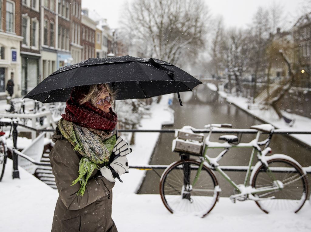Wandelaars in het winterse centrum van Utrecht. Veel mensen gaan eropuit om te genieten van het dikke pak sneeuw.