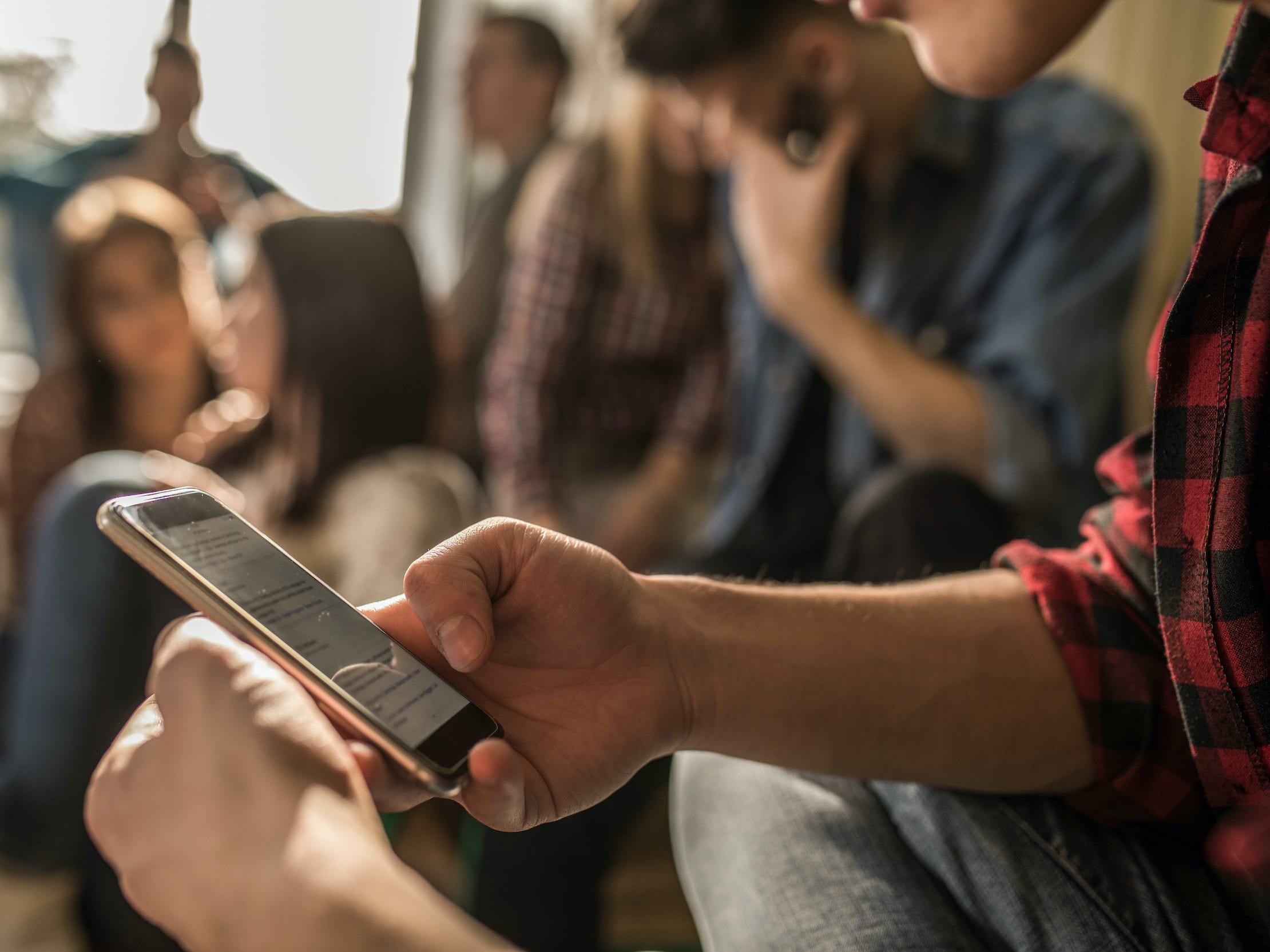 teen texting on phone in group of teens