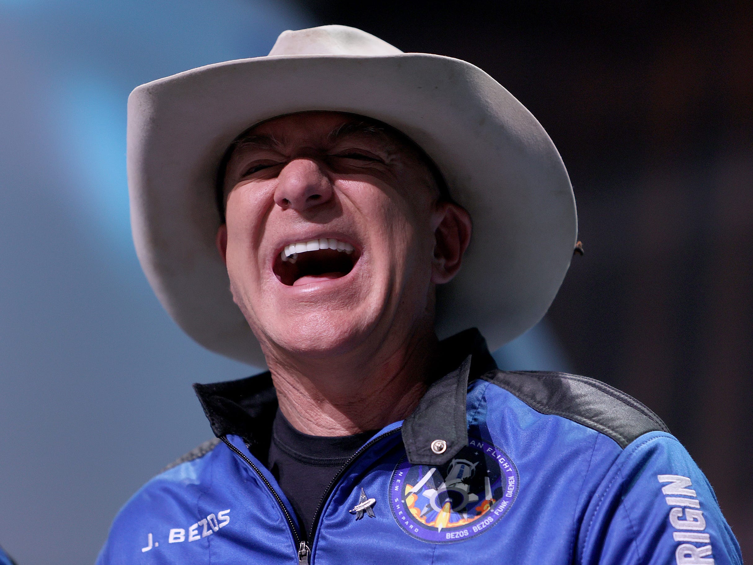 Jeff Bezos laughs wearing a cowboy hat