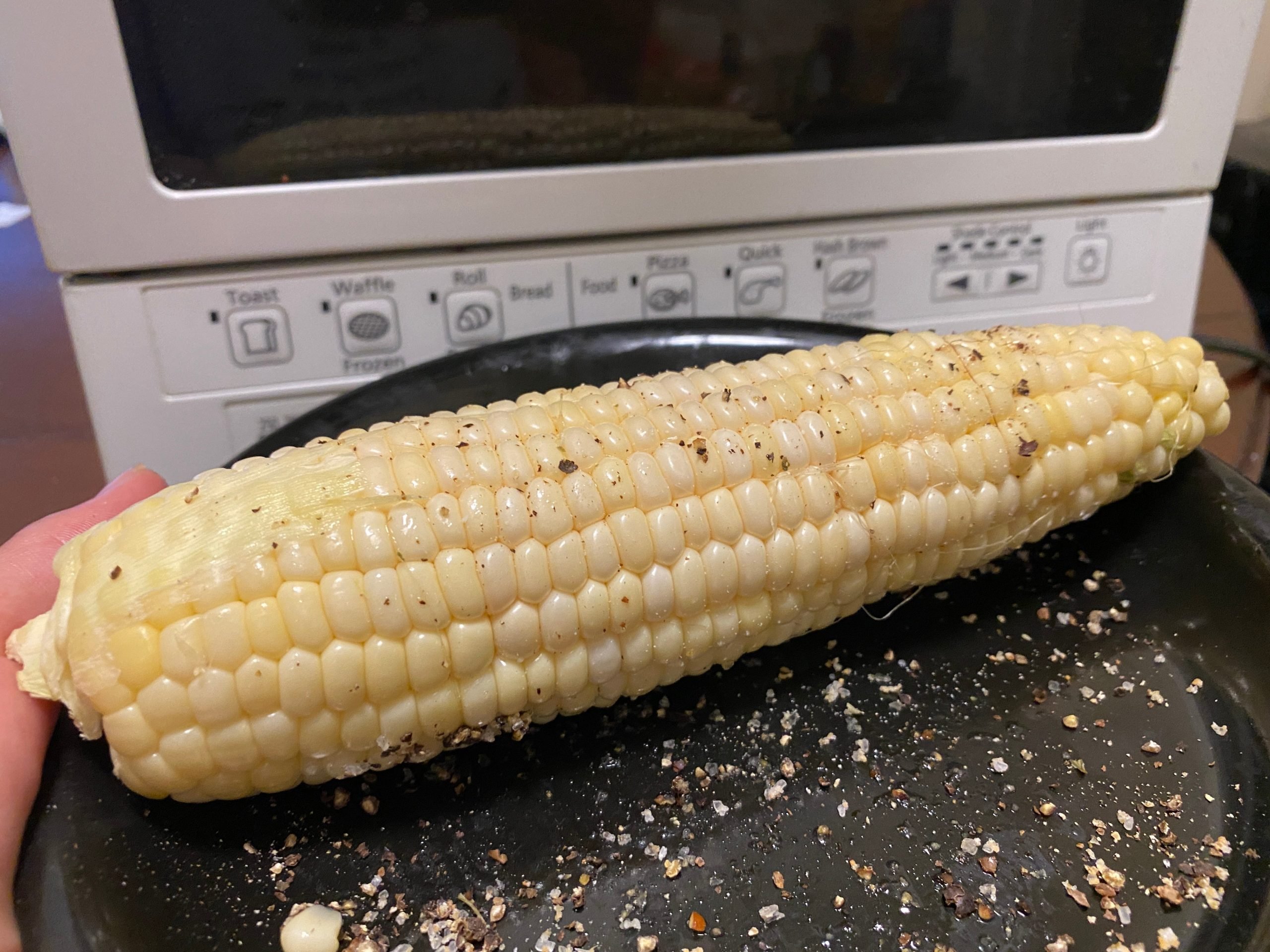Corn on the cob next to a toaster.