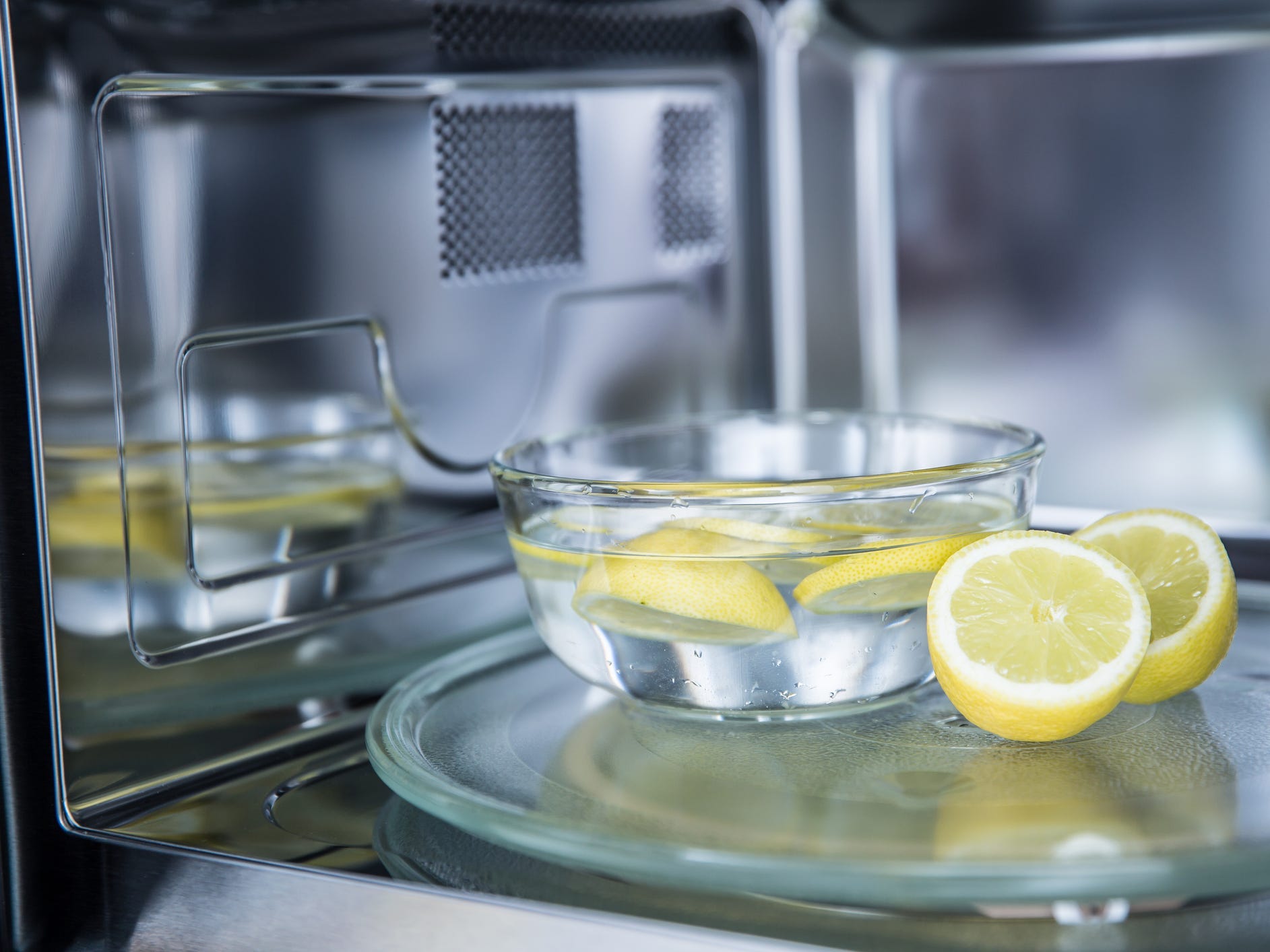 A bowl of water with lemon sliced floating in it sitting inside a microwave