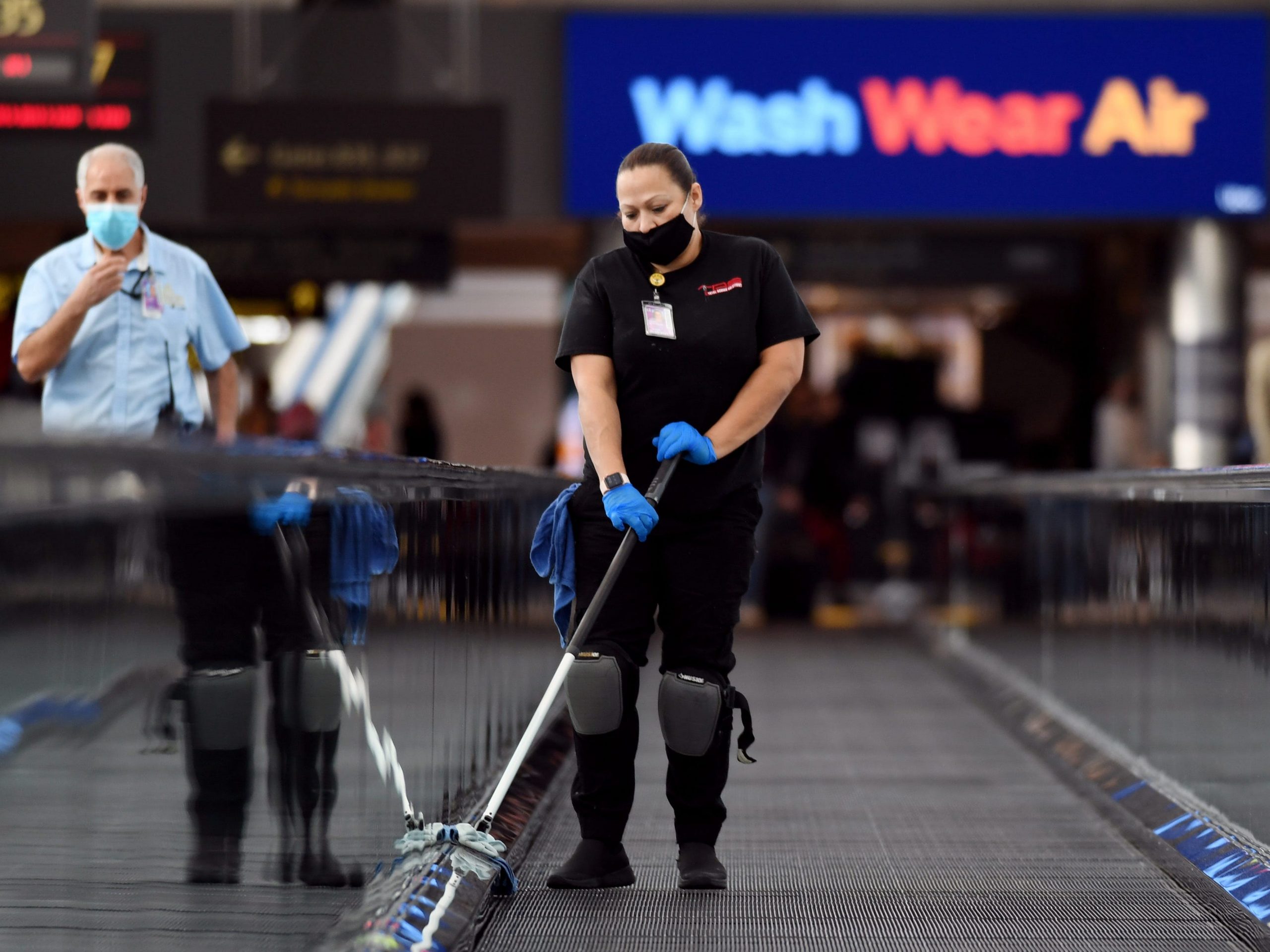 Janitor Mayra Hernandez, right, wiping hand rails at Concourse B of Denver International Airport in Denver, Colorado
