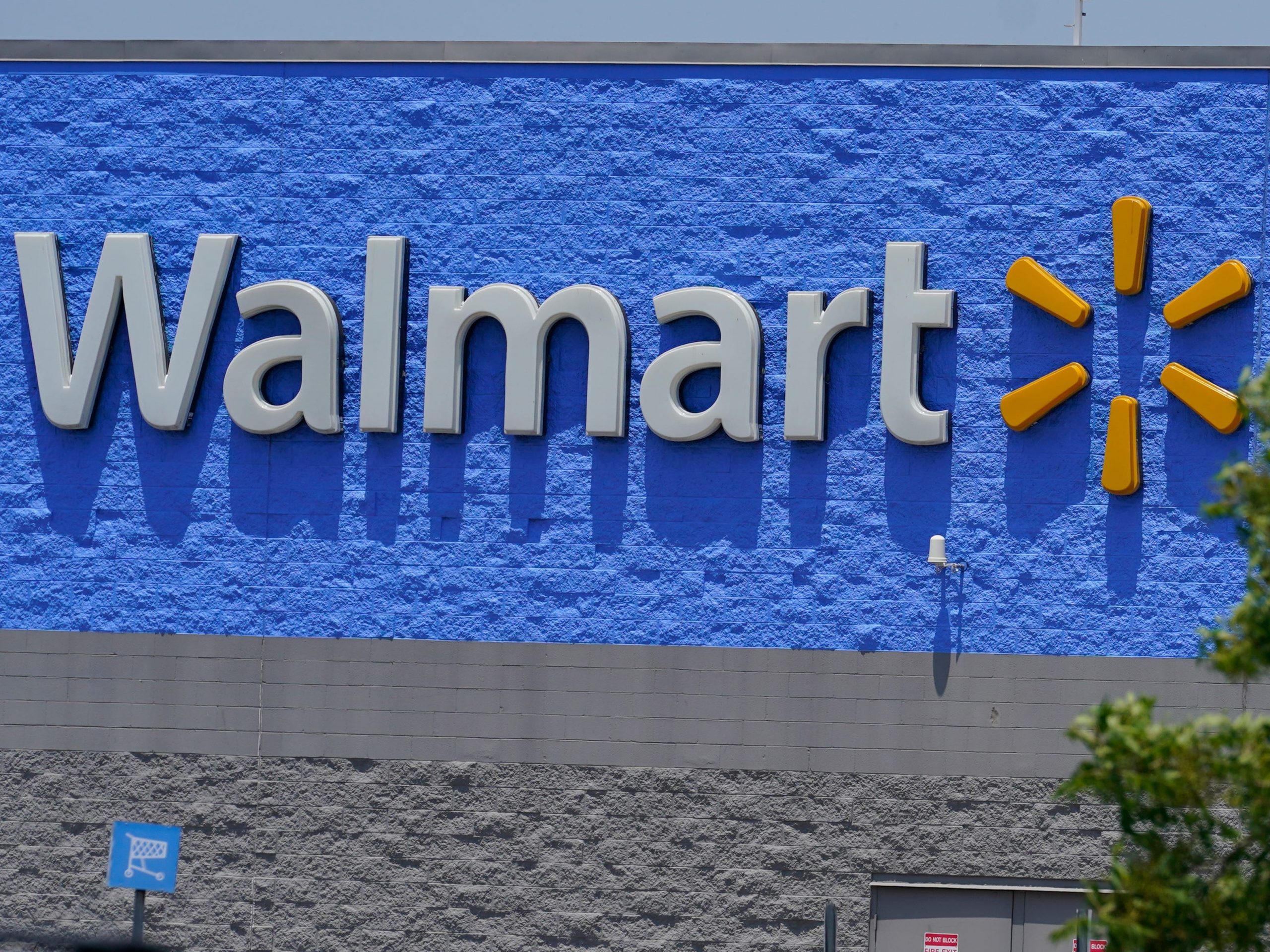 A Walmart sign on a blue painted wall on a sunny day