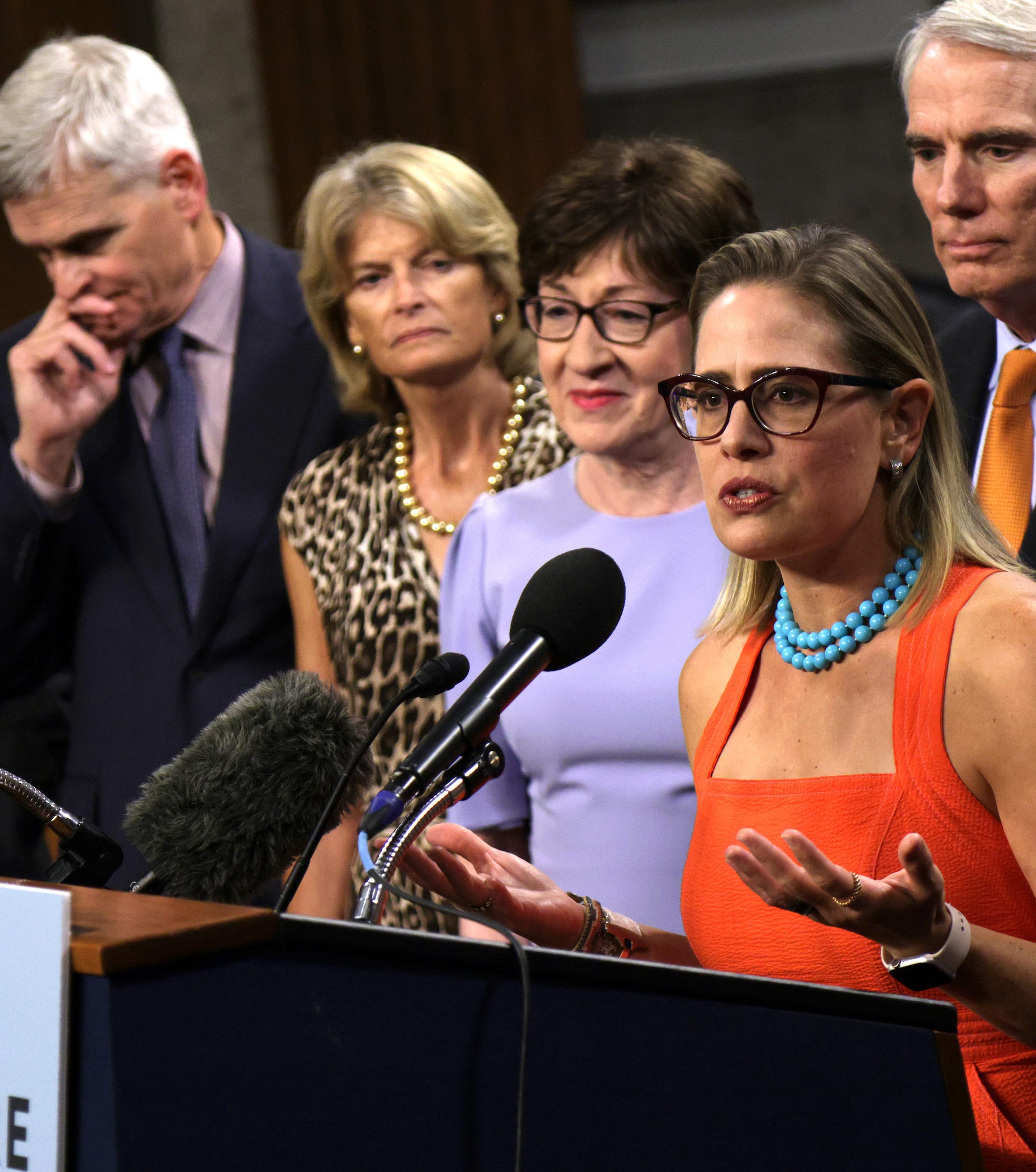 Democratic Sen. Kyrsten Sinema of Arizona speaks as Republican Sens. Lisa Murkowski of Alaska and Susan Collins of Maine stand by on Capitol Hill on July 28, 2021.