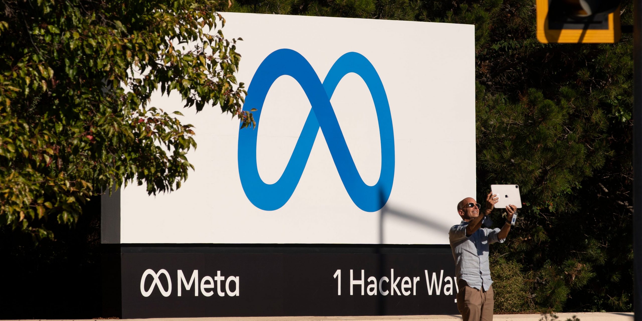 A man takes pictures in front of a sign showing logo of Meta outside Facebook headquarters on October 28, 2021 in Menlo Park, California.