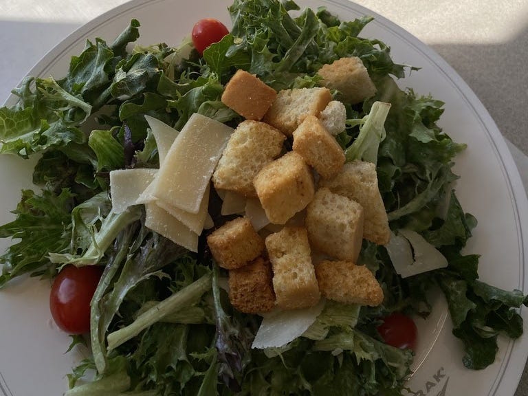 A fresh salad with croutons and orange juice.