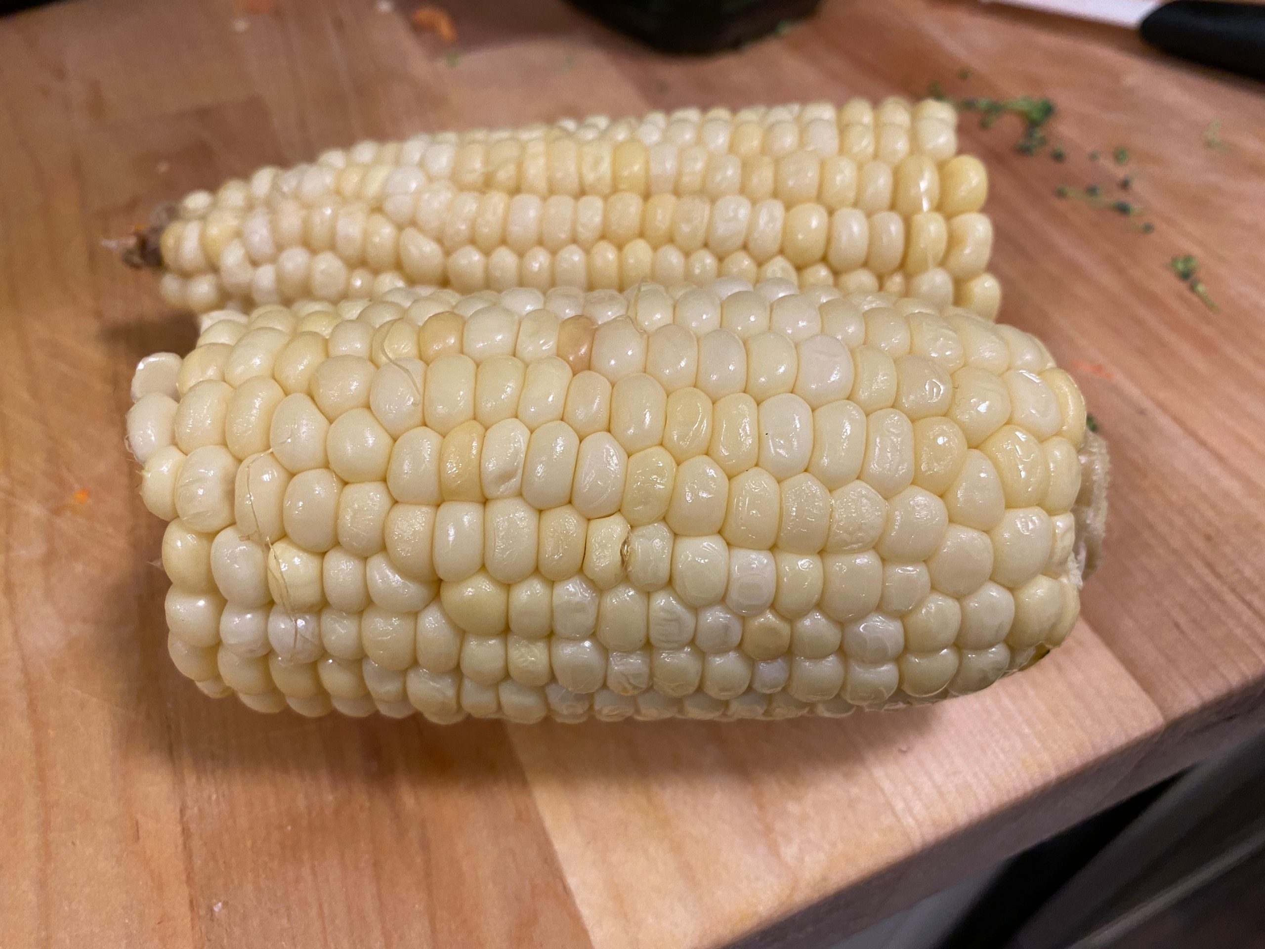 Two ears of corn on a wooden table.