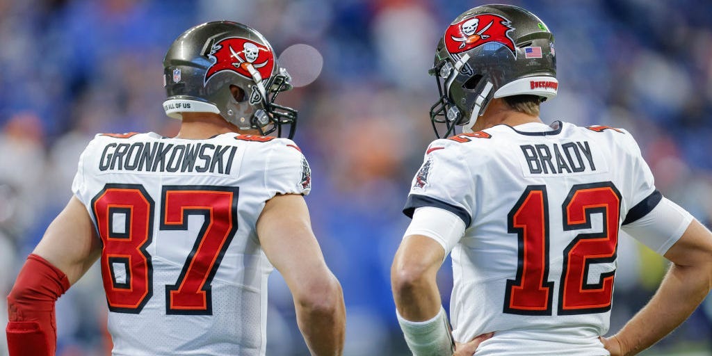 Rob Gronkowski #87 and Tom Brady #12 stand with their backs to the camera.
