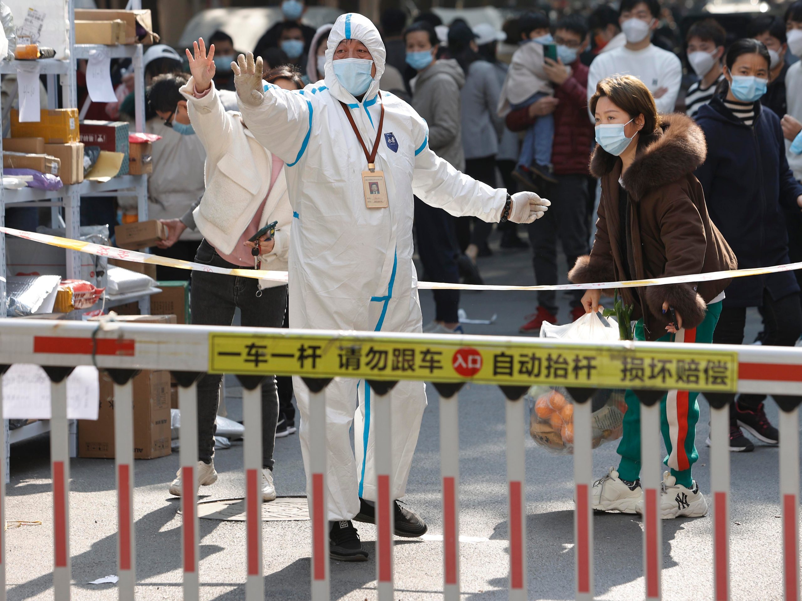 A volunteer wearing PPE raises their hand at a residential gate.