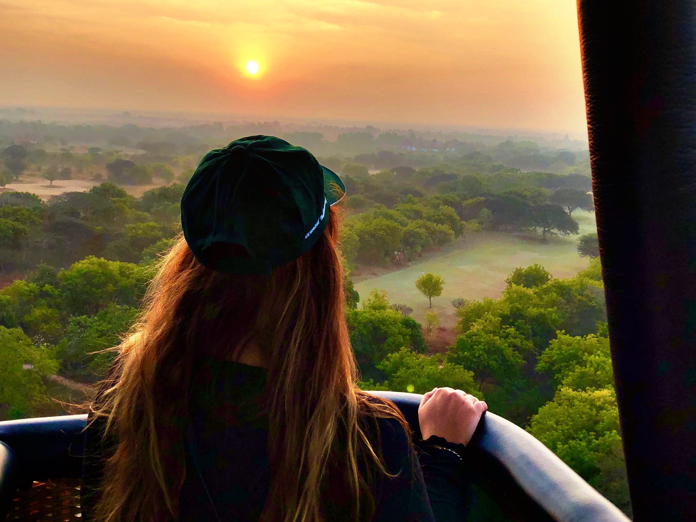 the writer's back asshe looks at a sunrise over trees