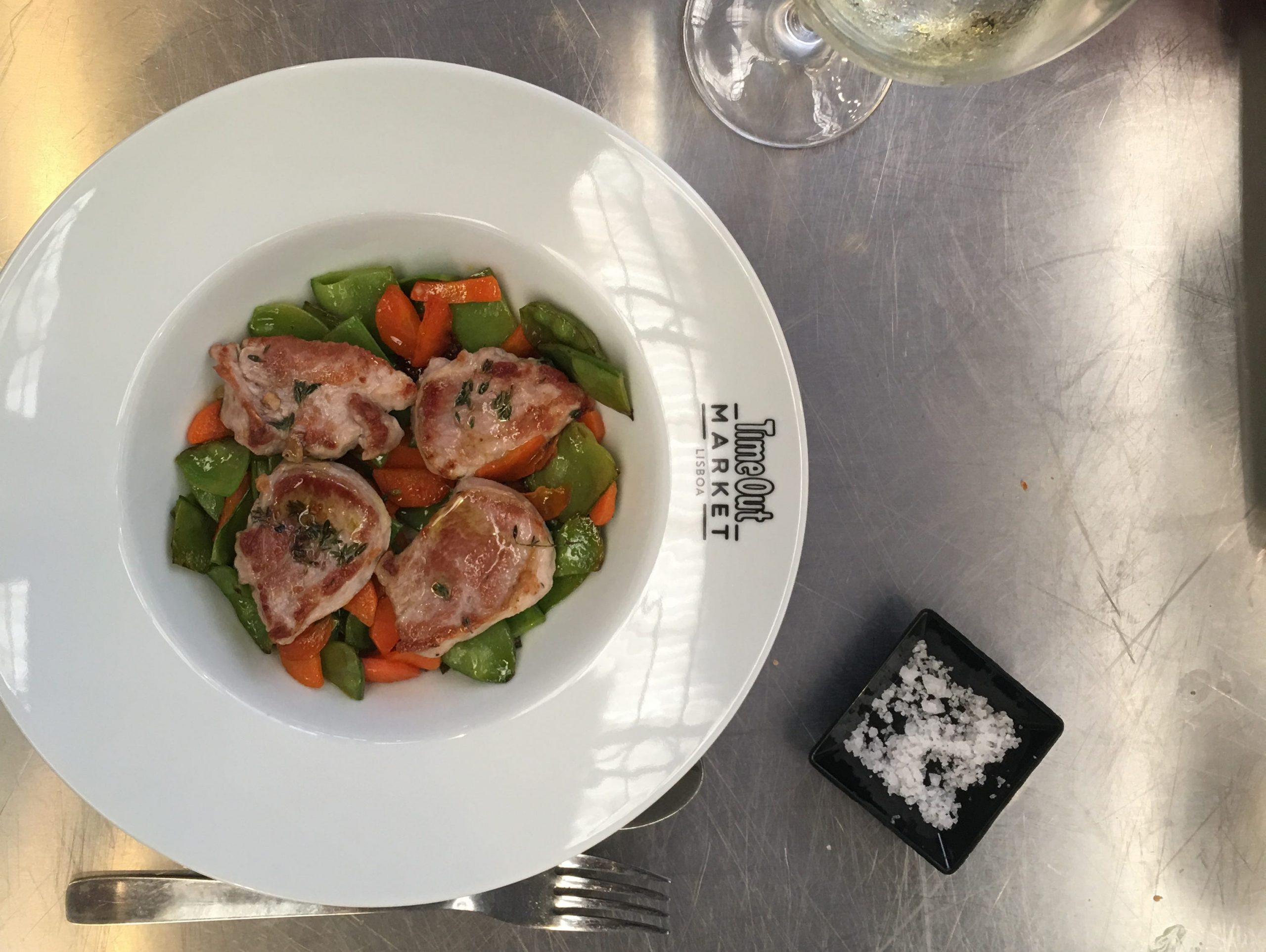 a glass of wine and a plate of food the writer made on a stainless-steel surface