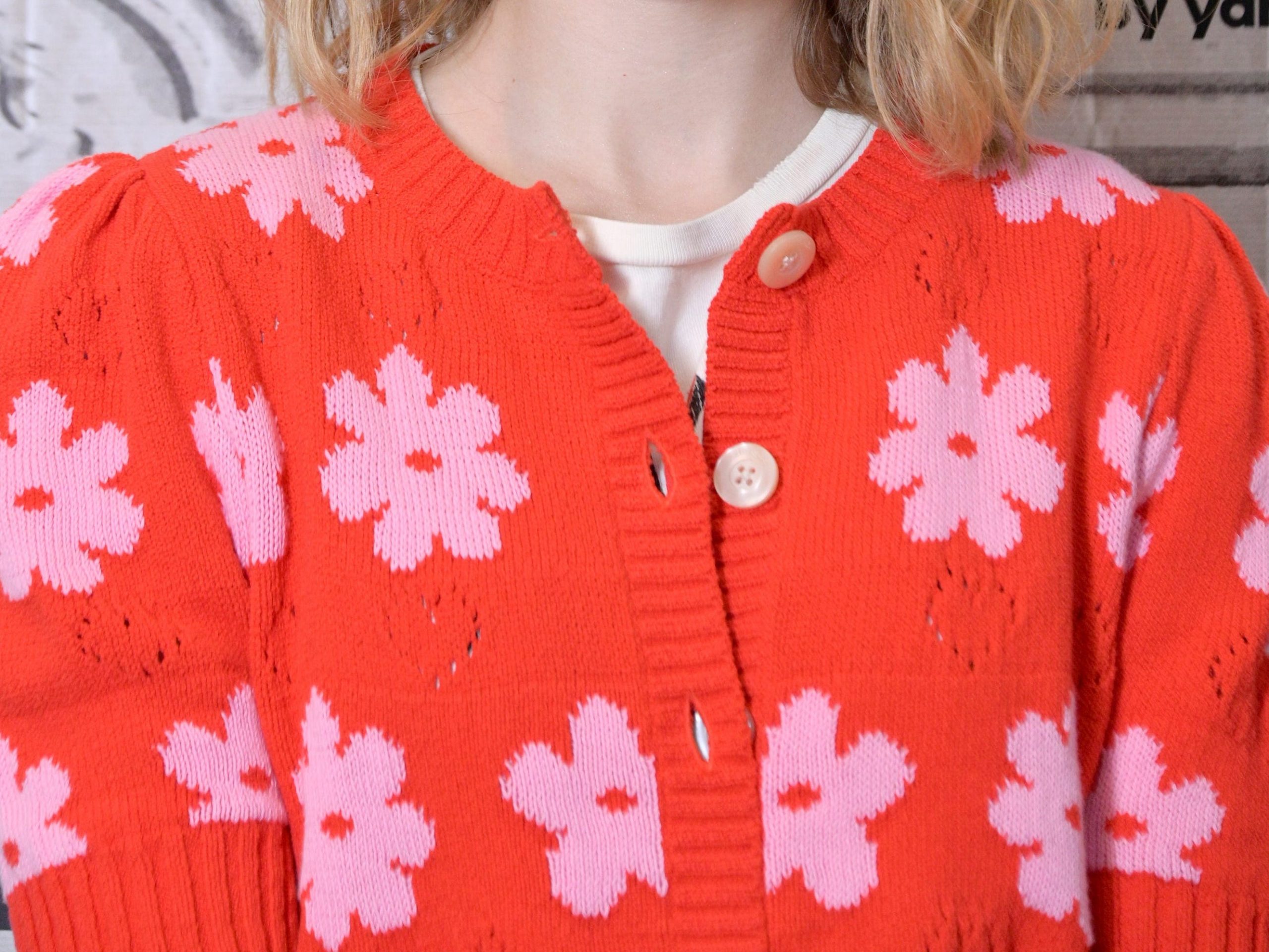 Millicent Simmonds in an orange cardigan with pink flowers.