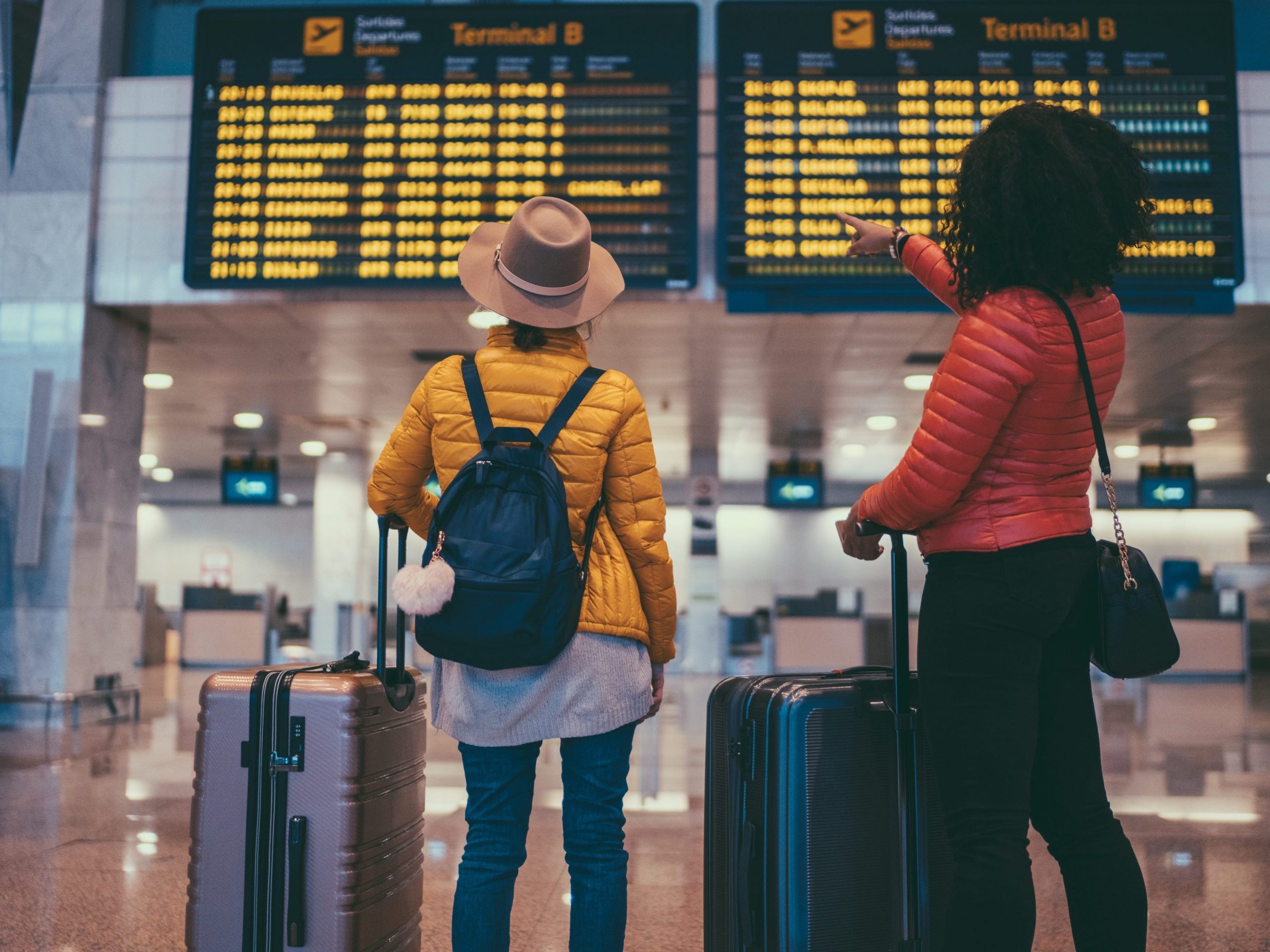 Two blacks read terminal signs in an airport.