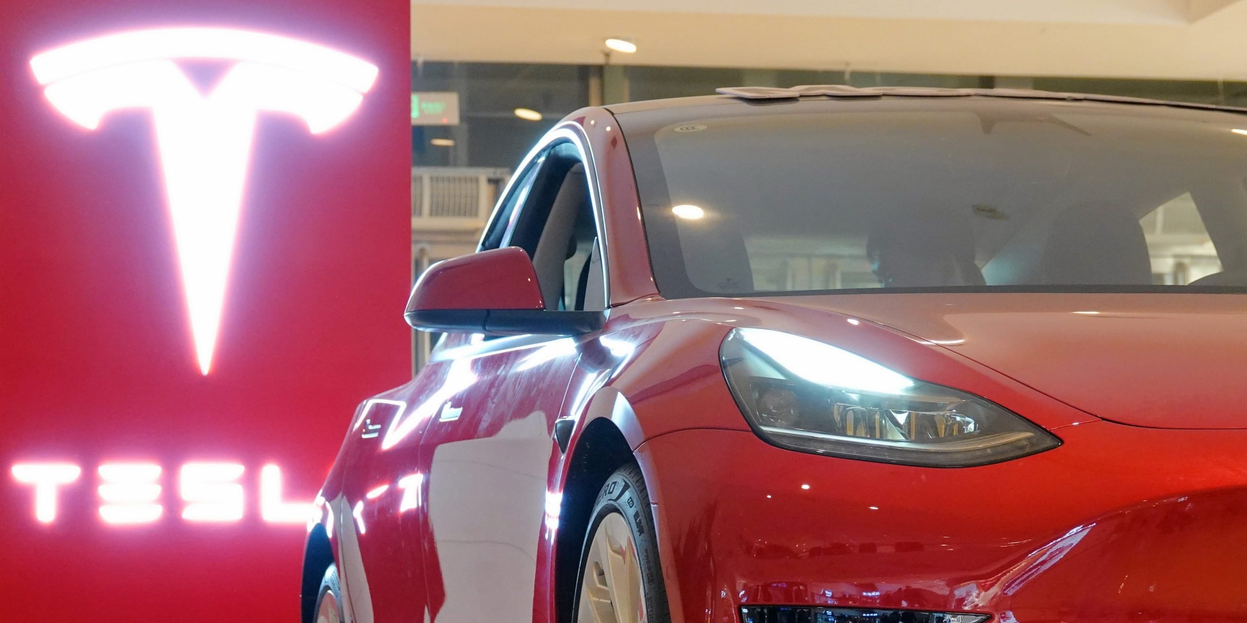 A red Tesla Model 3 in a showroom.