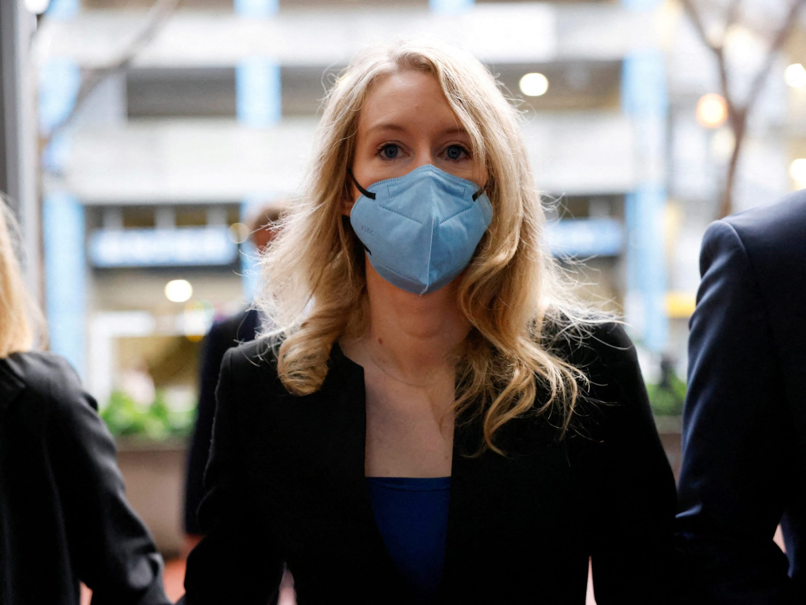 Theranos founder Elizabeth Holmes wears a blue mask walking to federal court