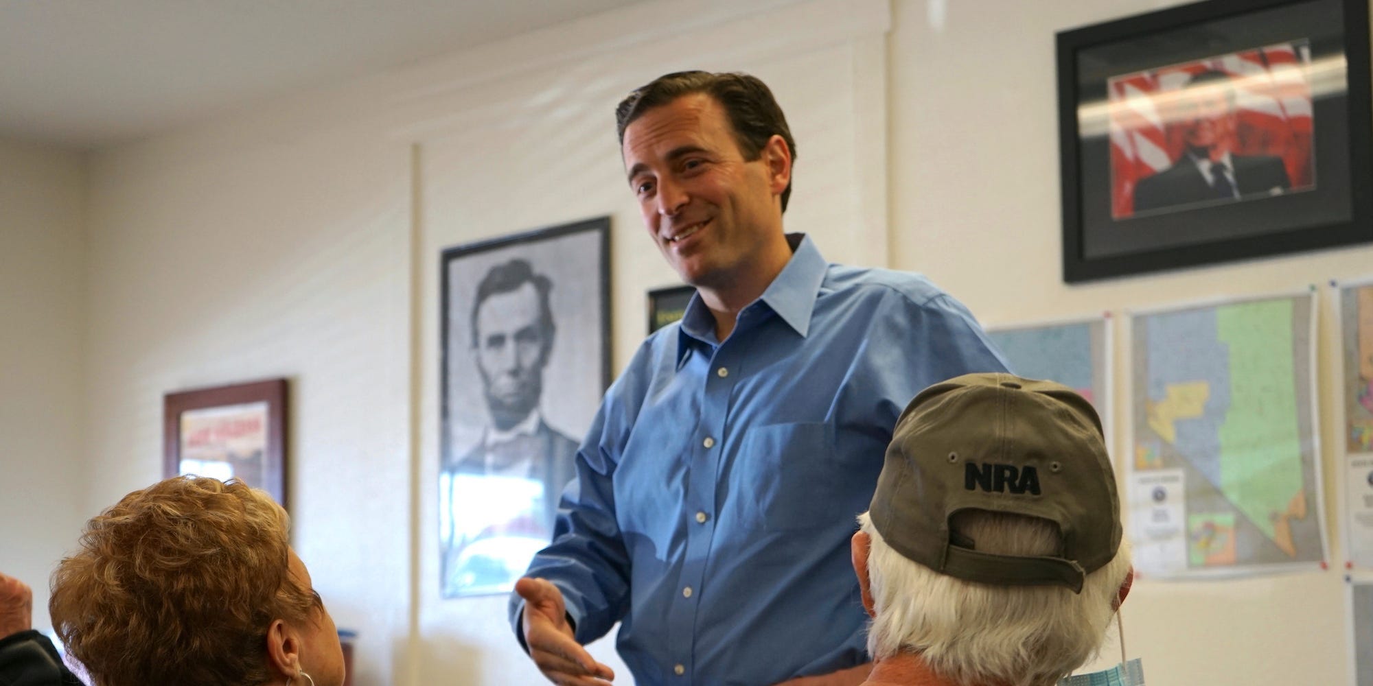 In this Sunday, Oct. 10, 2021, photo Republican Adam Laxalt, flanked by pictures of Presidents Abraham Lincoln and Ronald Reagan, talks to a supporter at the Douglas County Republican Party Headquarters on the final day of his Senate campaign's statewide tour in Gardnerville, Nev