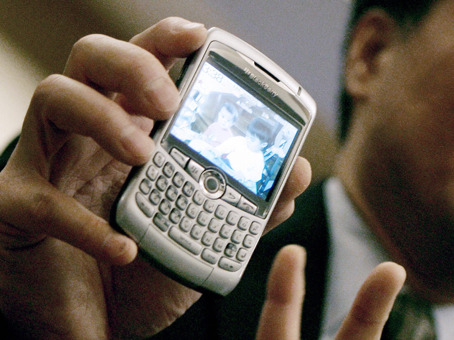Man holds up a silver Blackberry phone