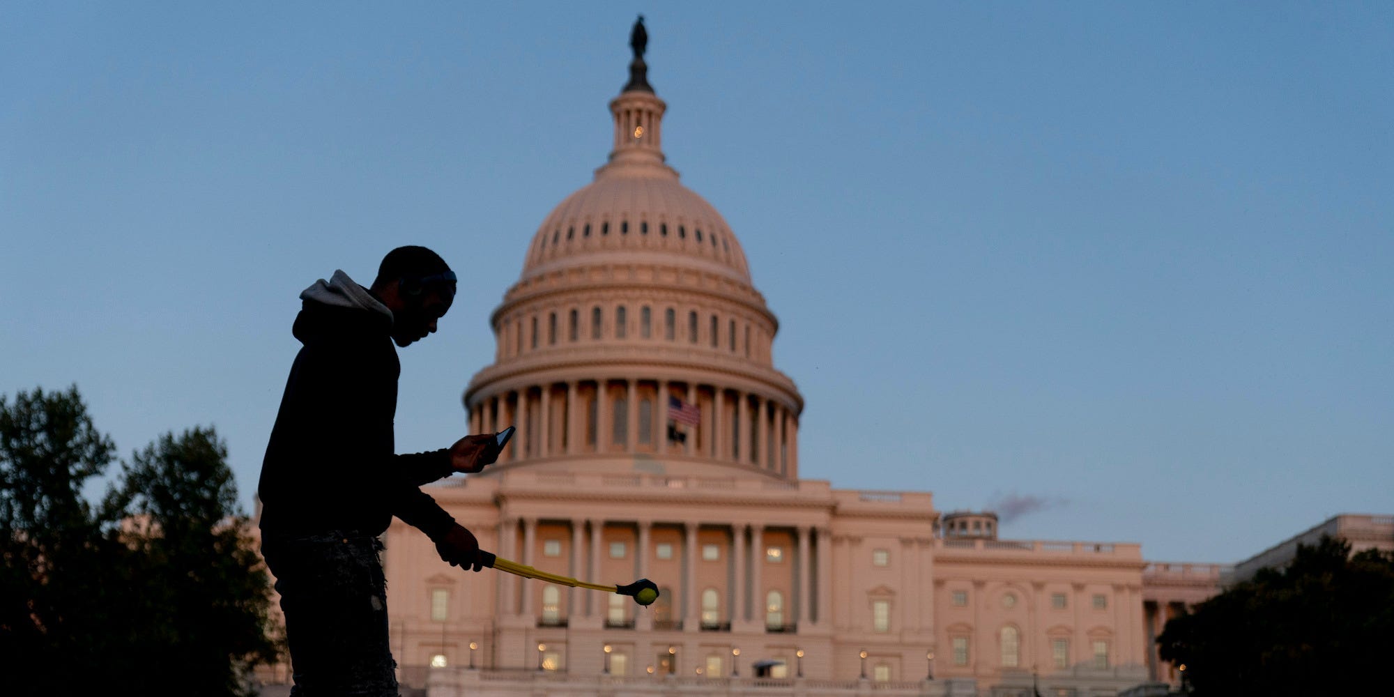 The U.S Capitol is visible at sunset as a man plays fetch with a dog in Washington, Thursday, Sept. 30, 2021