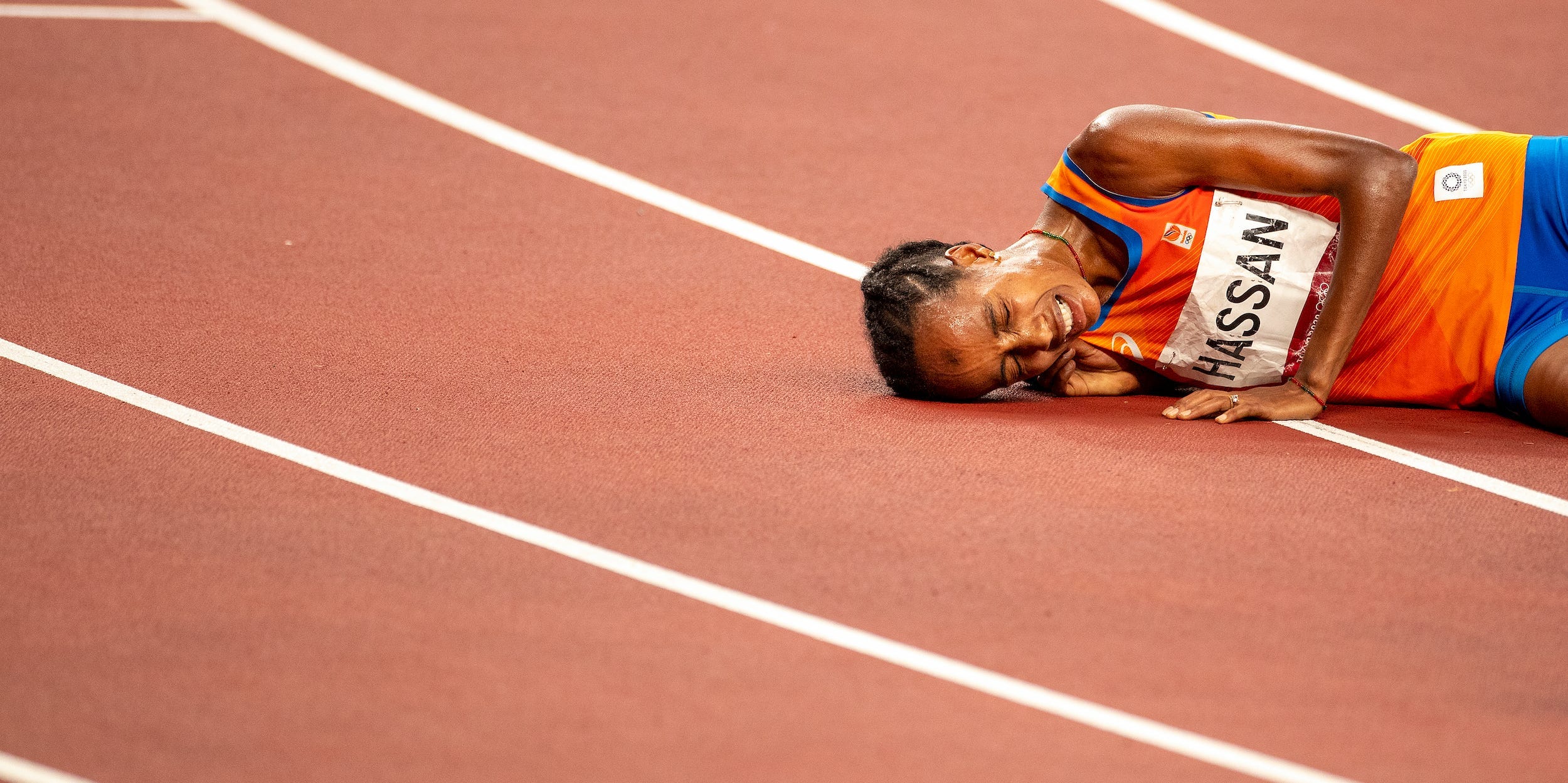 Sifan Hassan collapses on track after winning the 10,000 meter final at the Tokyo 2020 Olympics.