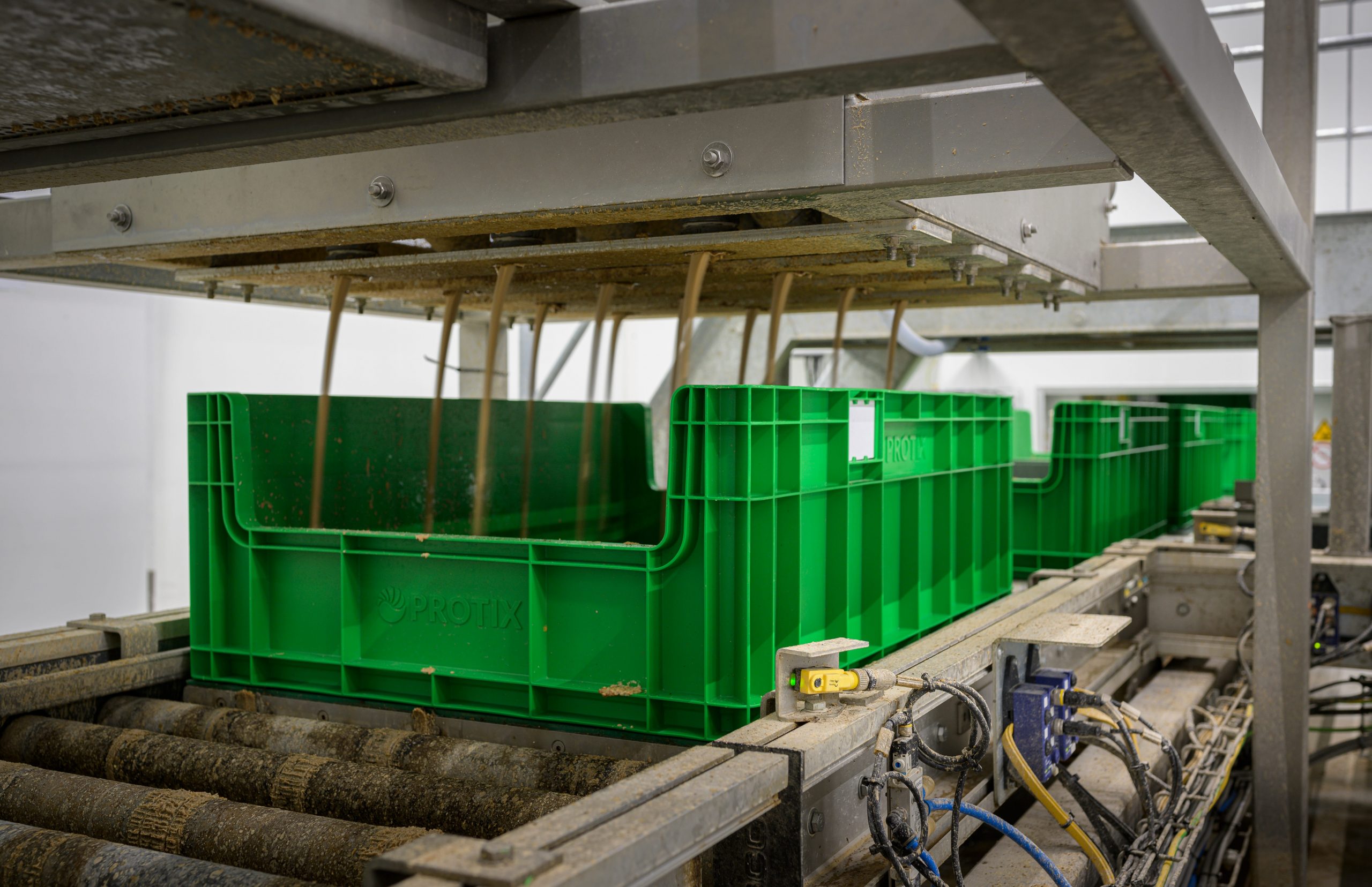 Large green crates with wires attached on a conveyor belt