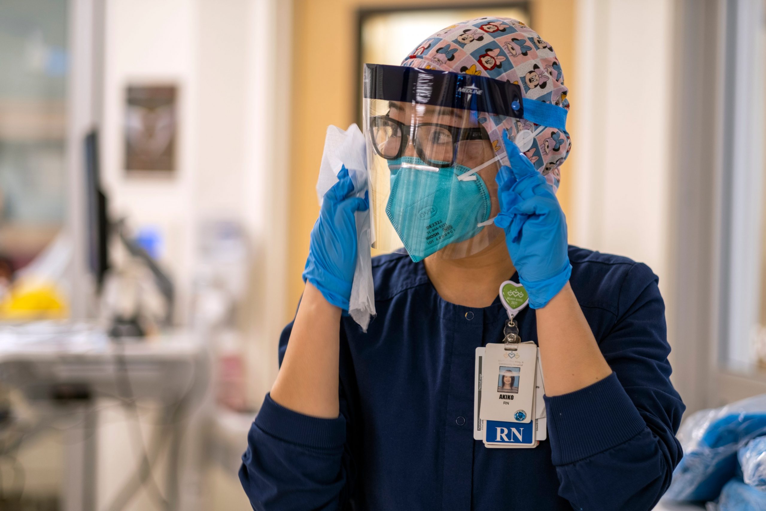 Registered nurse Akiko Gordon looks around the ICU while wearing a face shield, N95 mask, and scrubs.