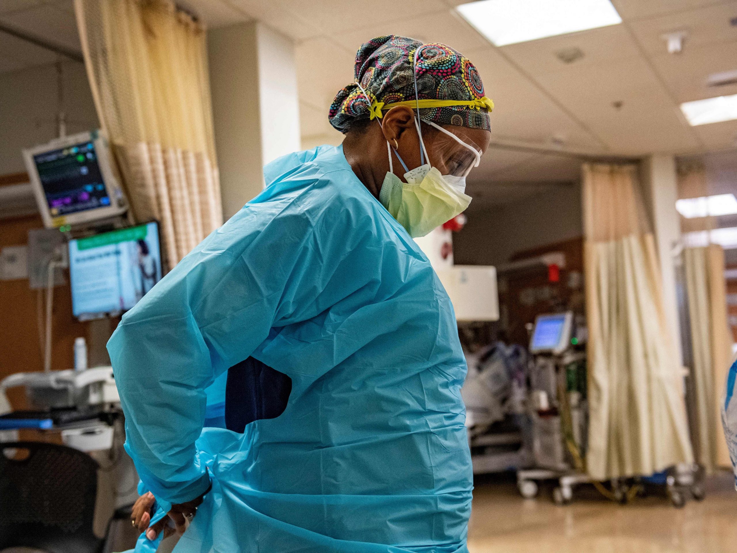A medical worker at UMass Memorial Medical Center ties her PPE around her back while looking down.
