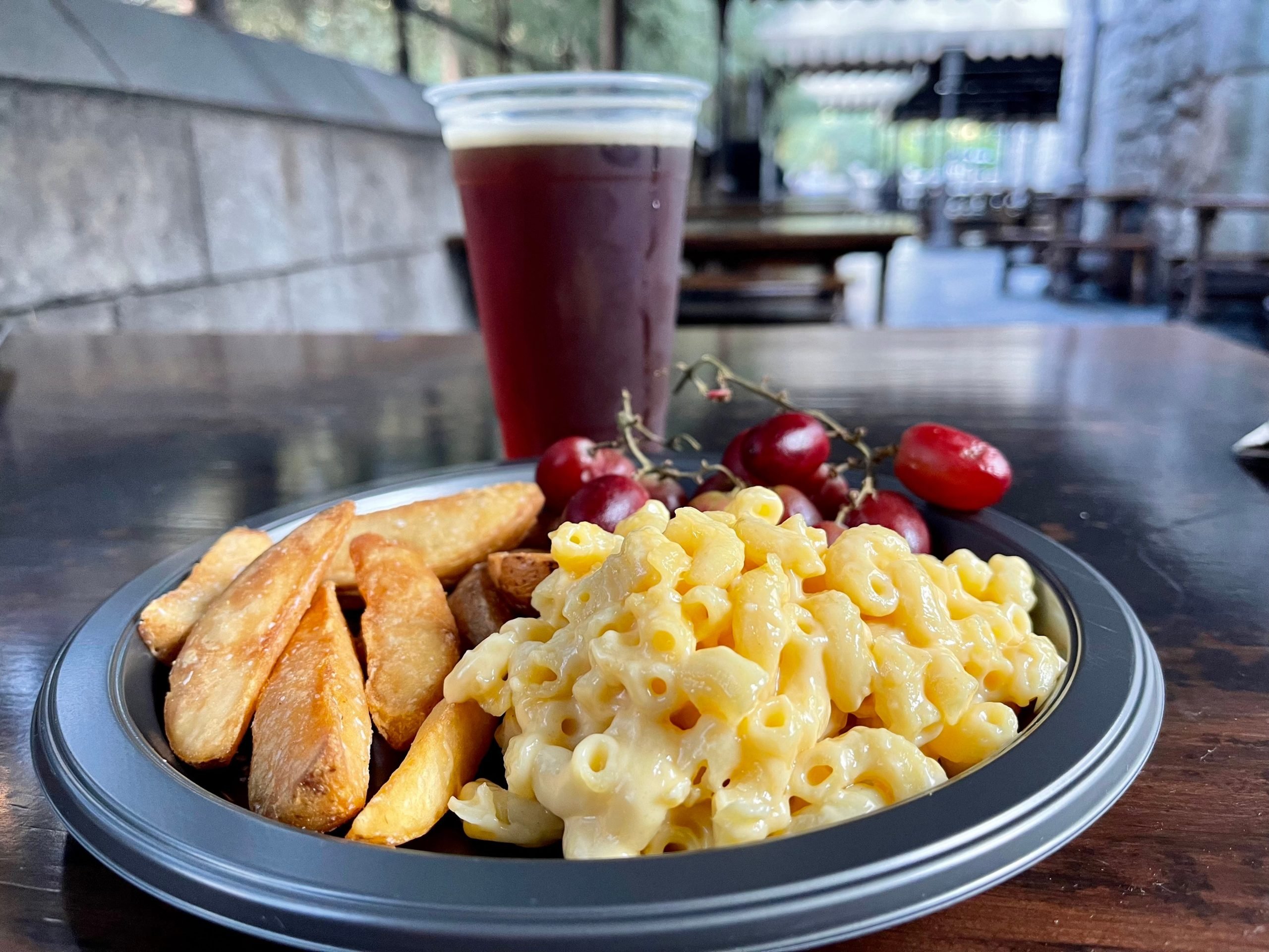 A universal meal with a soda, potato wedges and mac and cheese