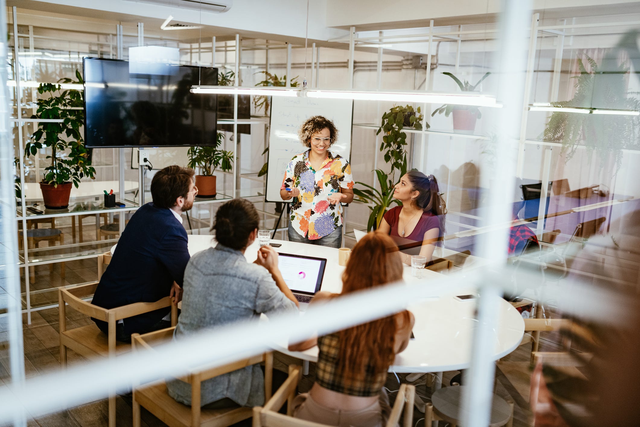 Group of creative entrepreneurs and business people working together in modern eco-friendly office with plants and recycled materials