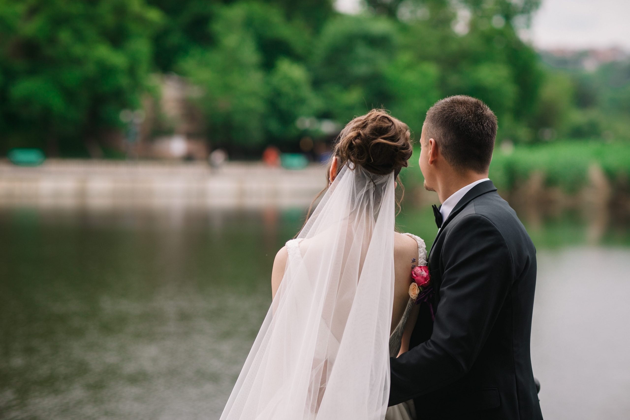 A bride and groom looking out into water and trees